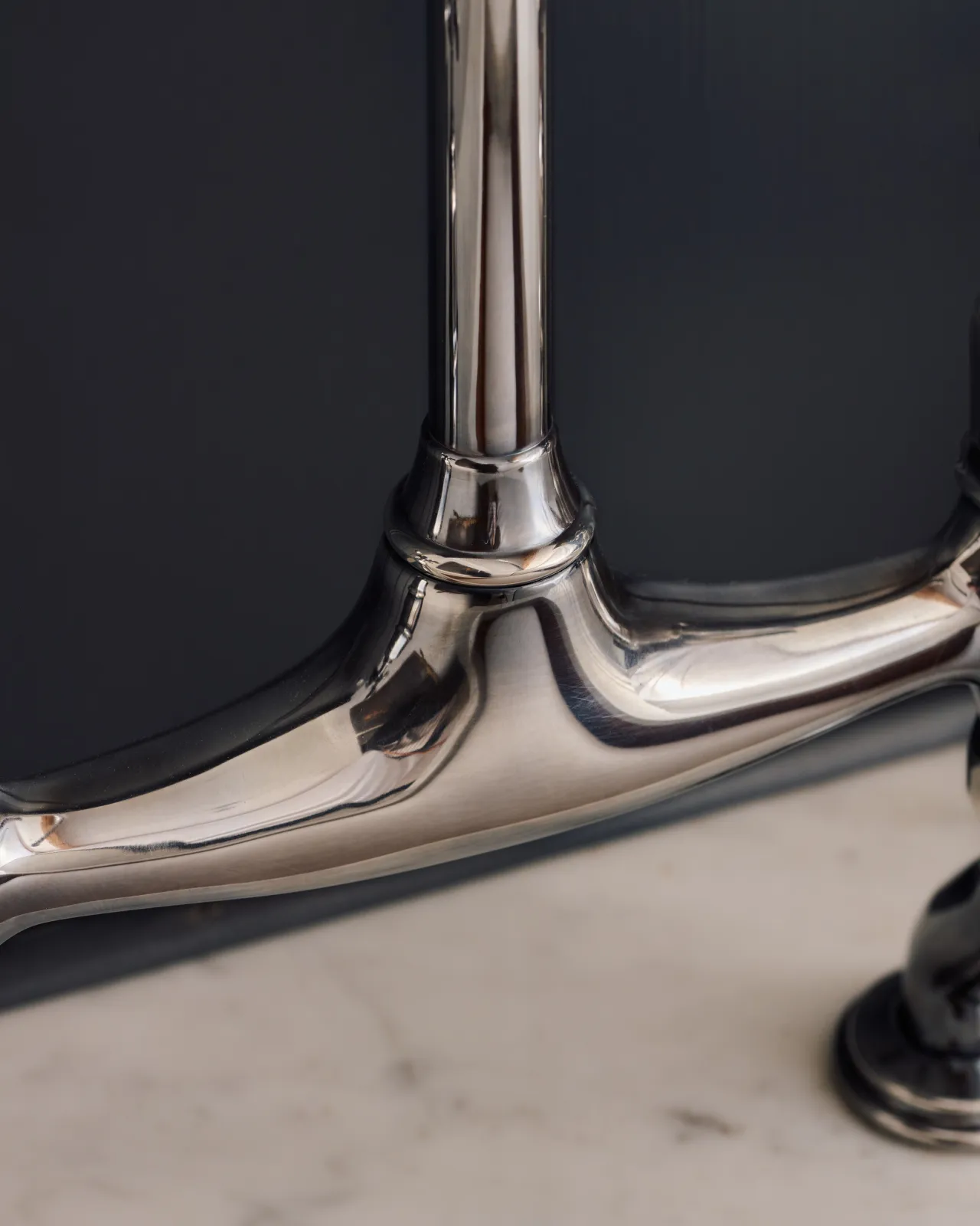 A close-up view of the body of a traditional-style tarnished silver mixer tap with crosshead handles.