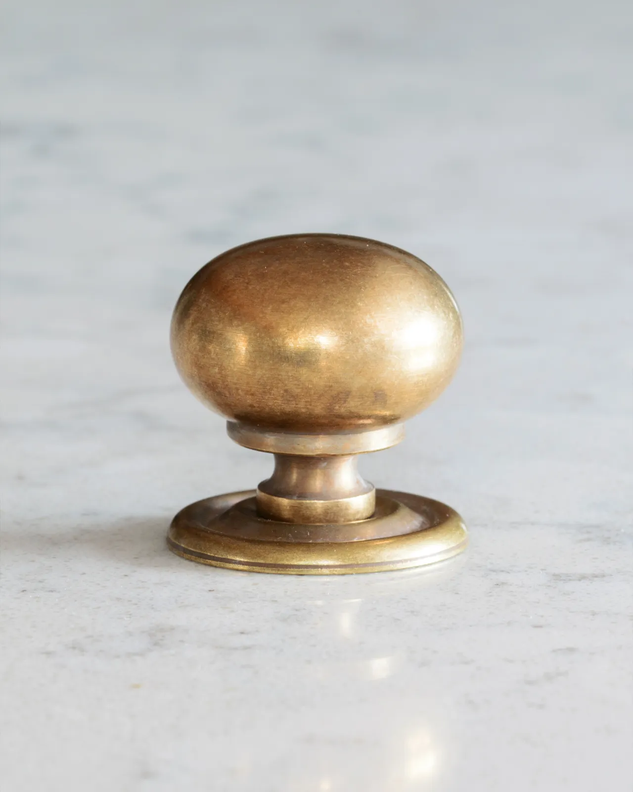A ‘Medium’ round doorknob with a pressed backplate for a kitchen cupboard or drawer in a burnished 'Bella' brass finish.