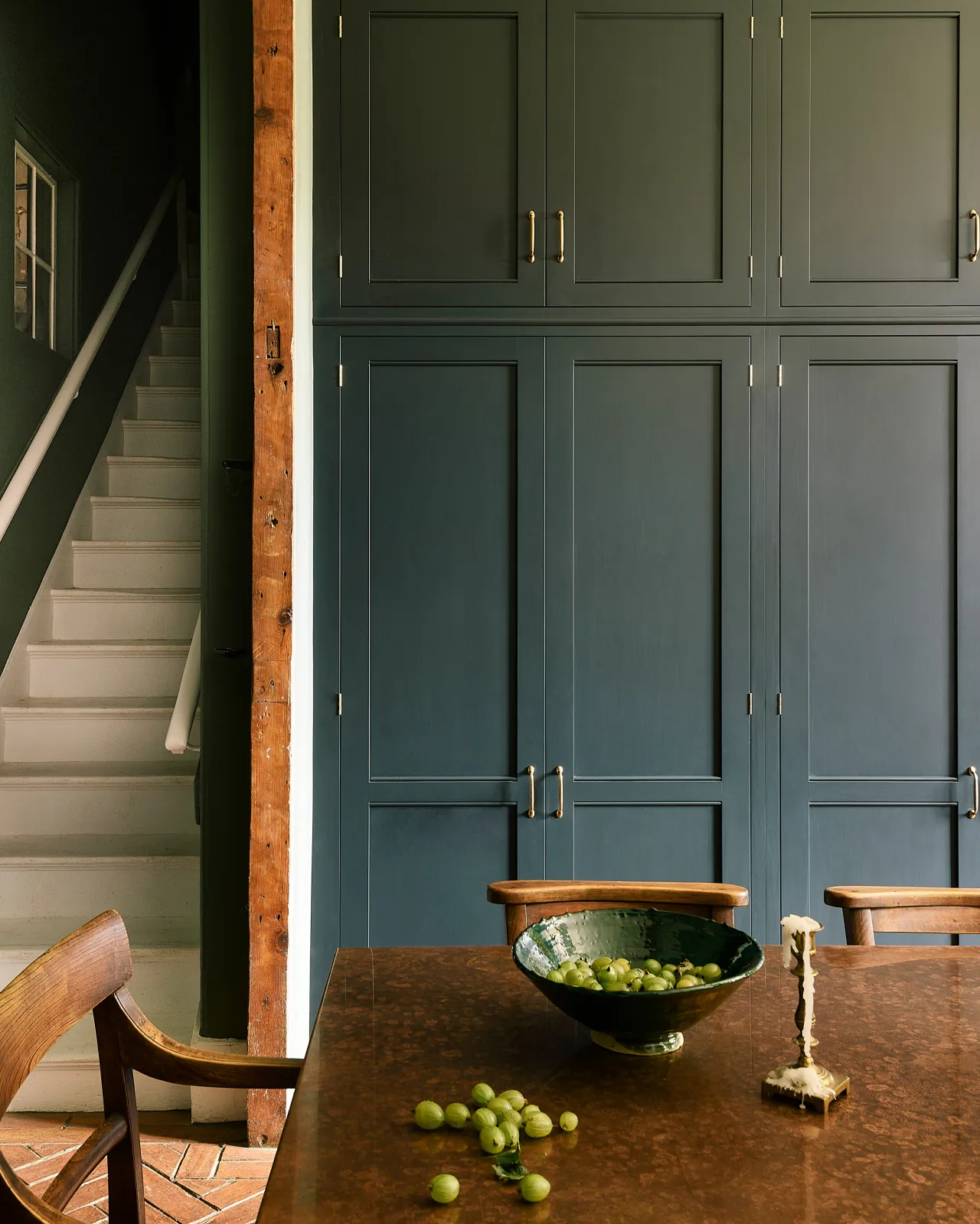 A straight-on view of dark blue painted tall Georgian-style pantry cupboards fitted with simple pull handles in a burnished 'Bella' brass finish.