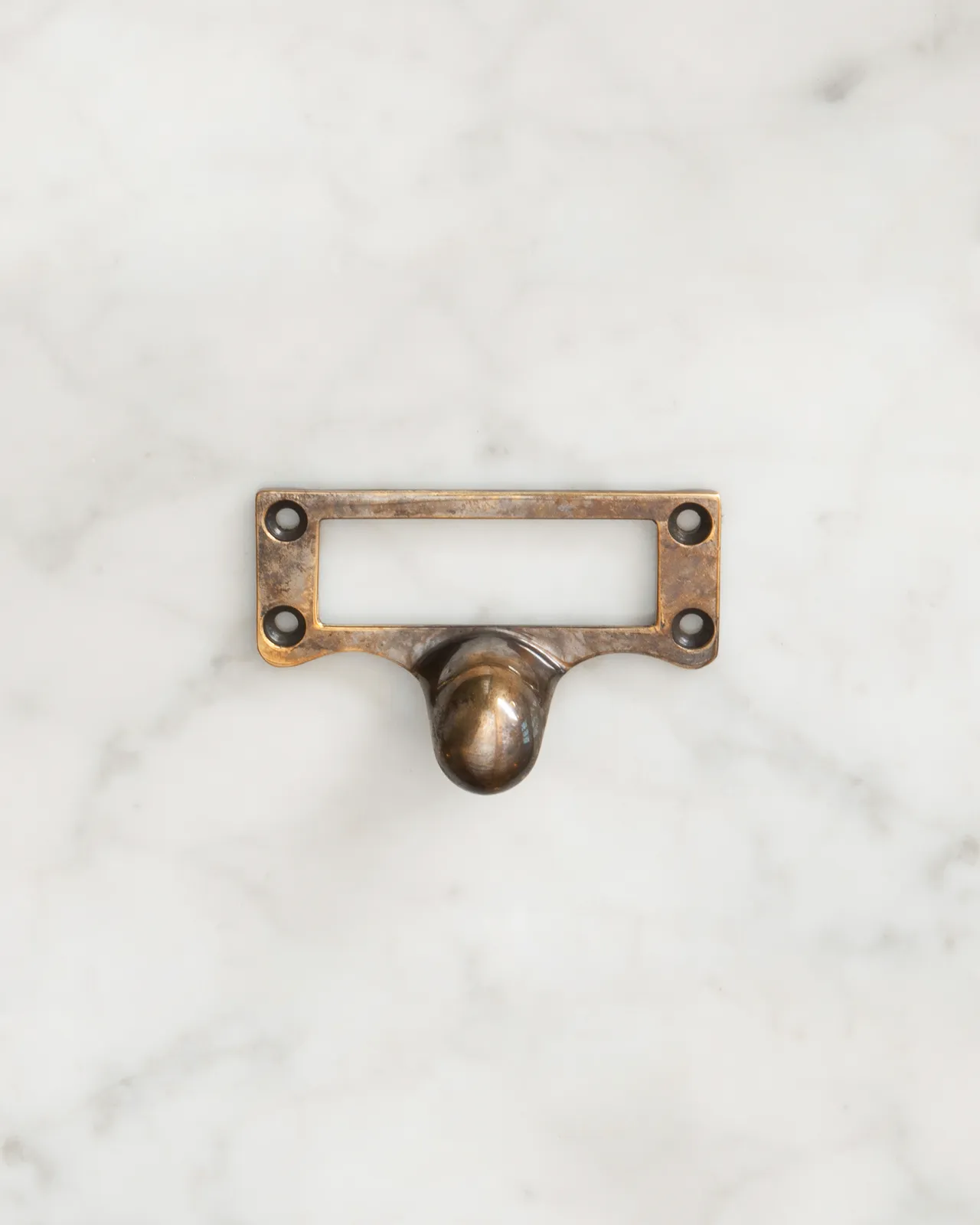 A small cardframe pull handle in a burnished 'Bella' brass finish.