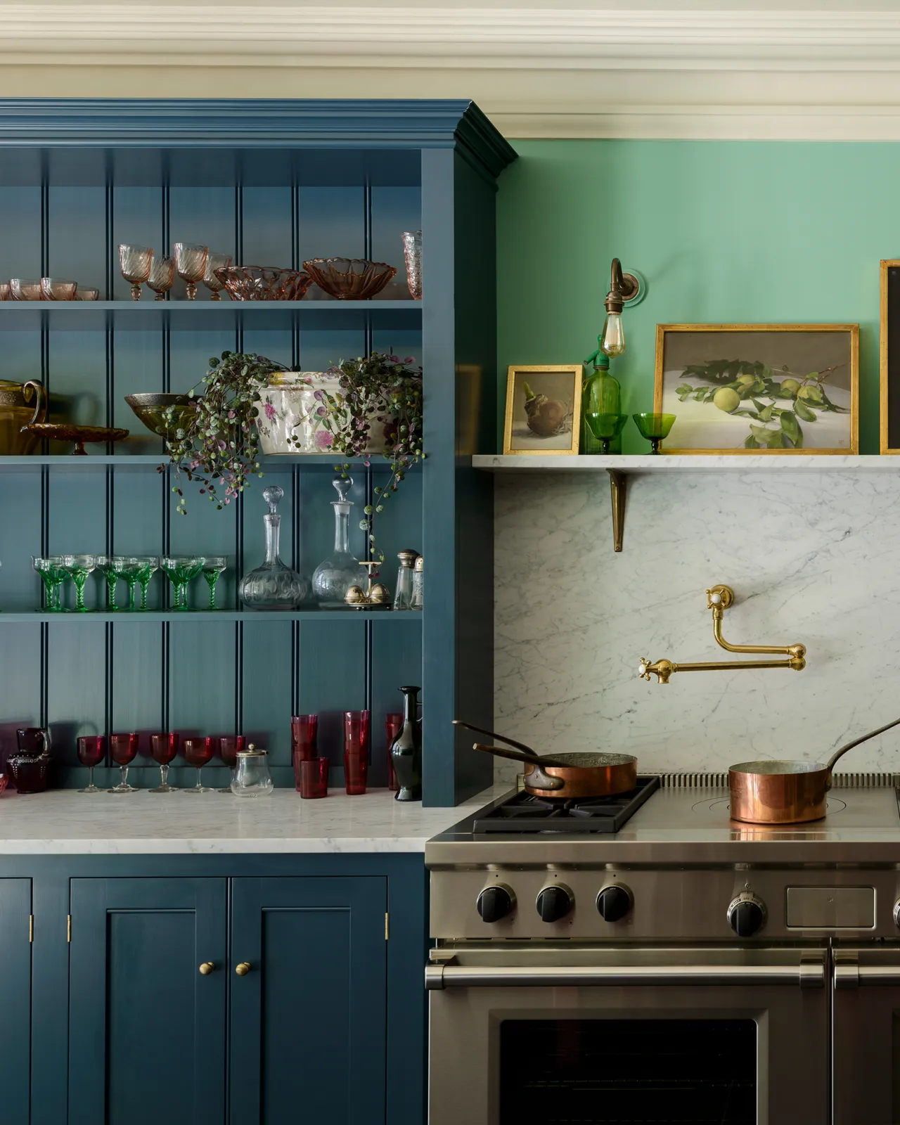 A straight-on view of Georgian-style kitchen cupboards with an open countertop stacked full of green and red coloured glasses.