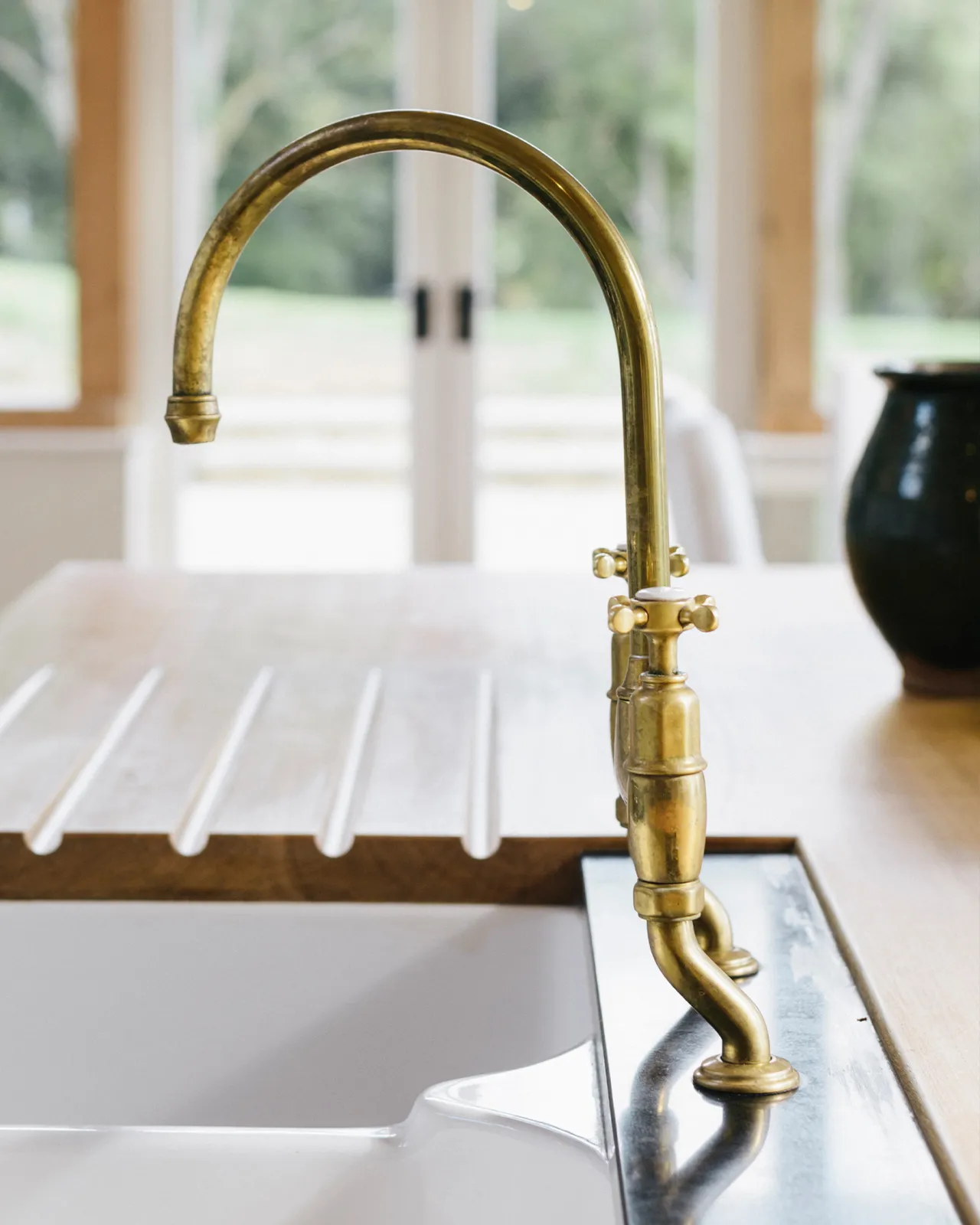 A profile view of a traditional-style aged brass mixer tap with crosshead handles.