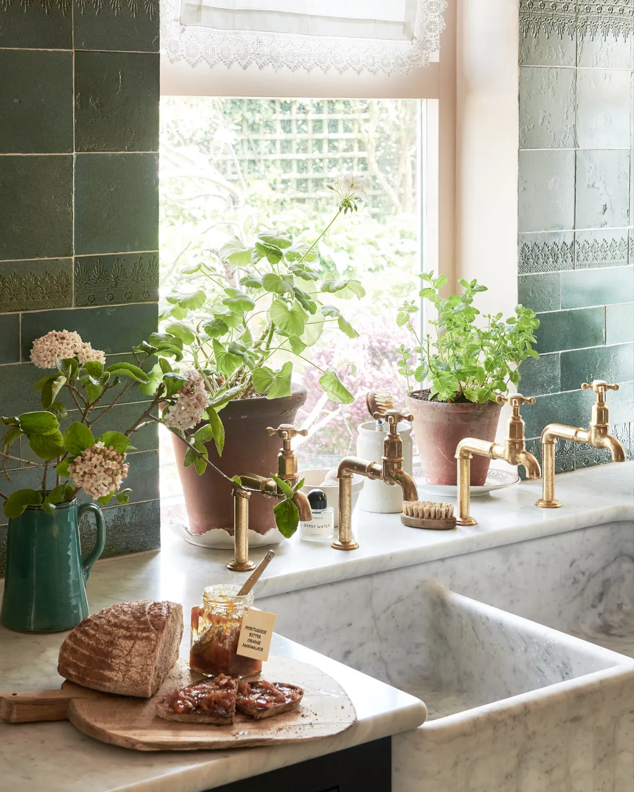 Two pairs of traditional-style aged brass bibcock taps installed over a grand double bowl Carrara marble sink.