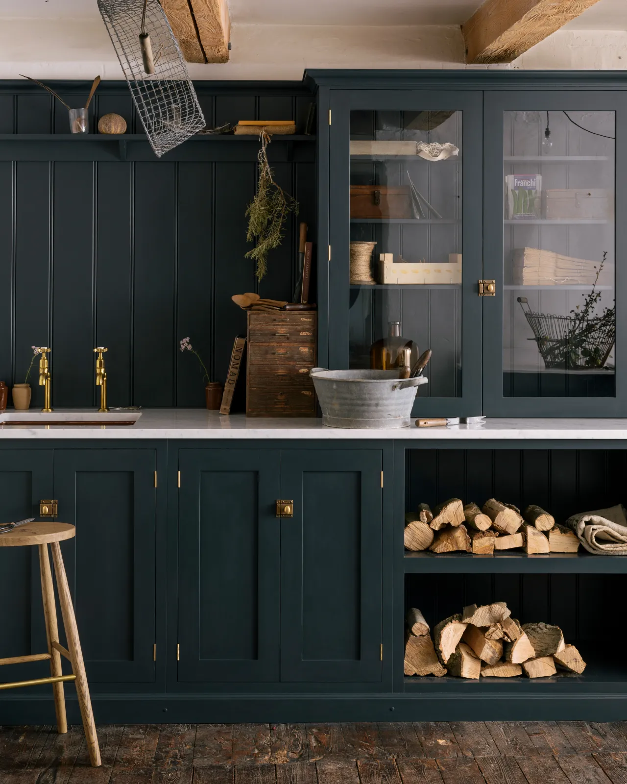 A straight-on view of a small Shaker-style utility kitchen with dark blue painted cupboards and square cupboard catches in a burnished 'Bella' brass finish.