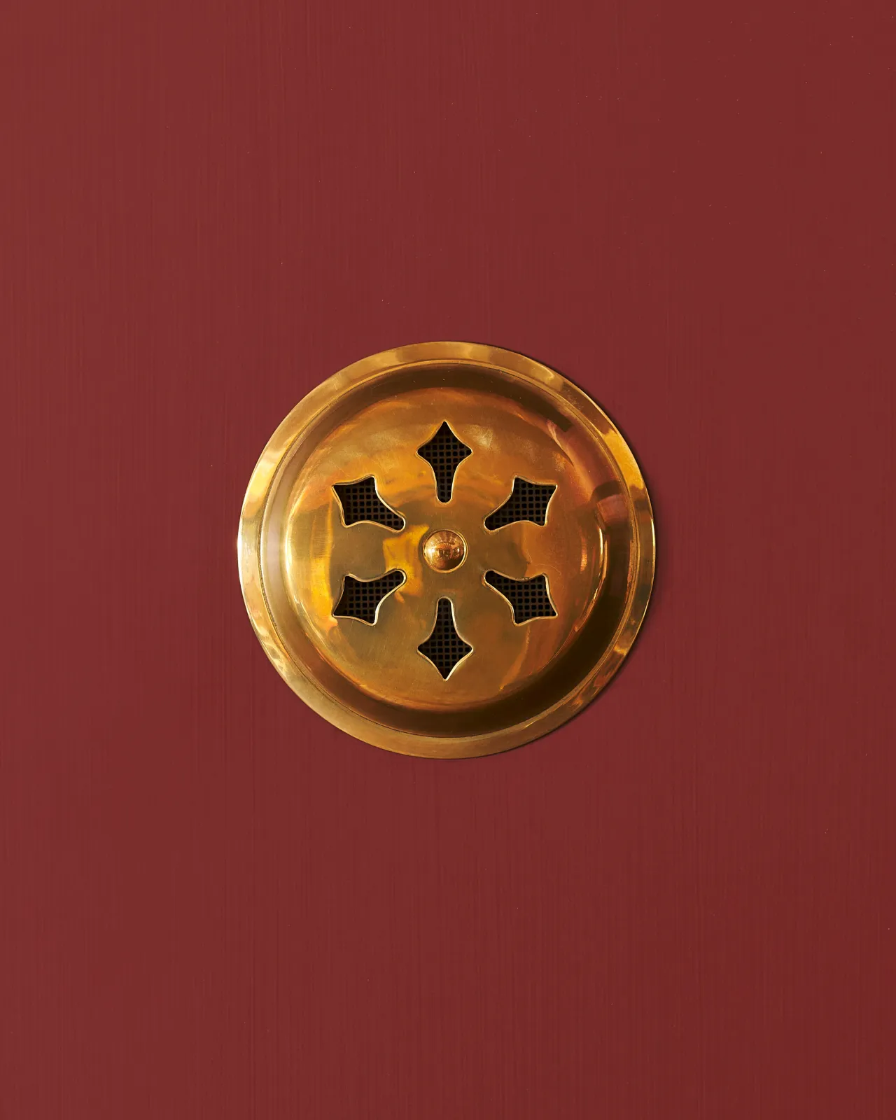 A Victorian-inspired circular brass ventilation grille with traditional decorative cutouts.