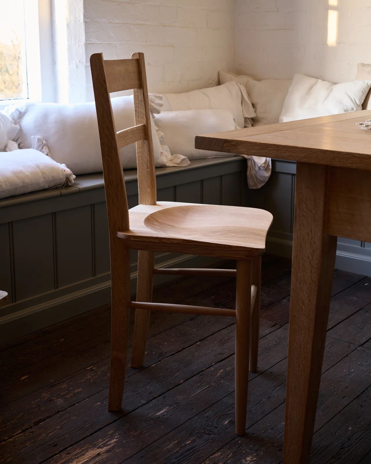 An oblique view of a mid-century-style dining chair with a sculpted ash seat pan and oak legs and frame.