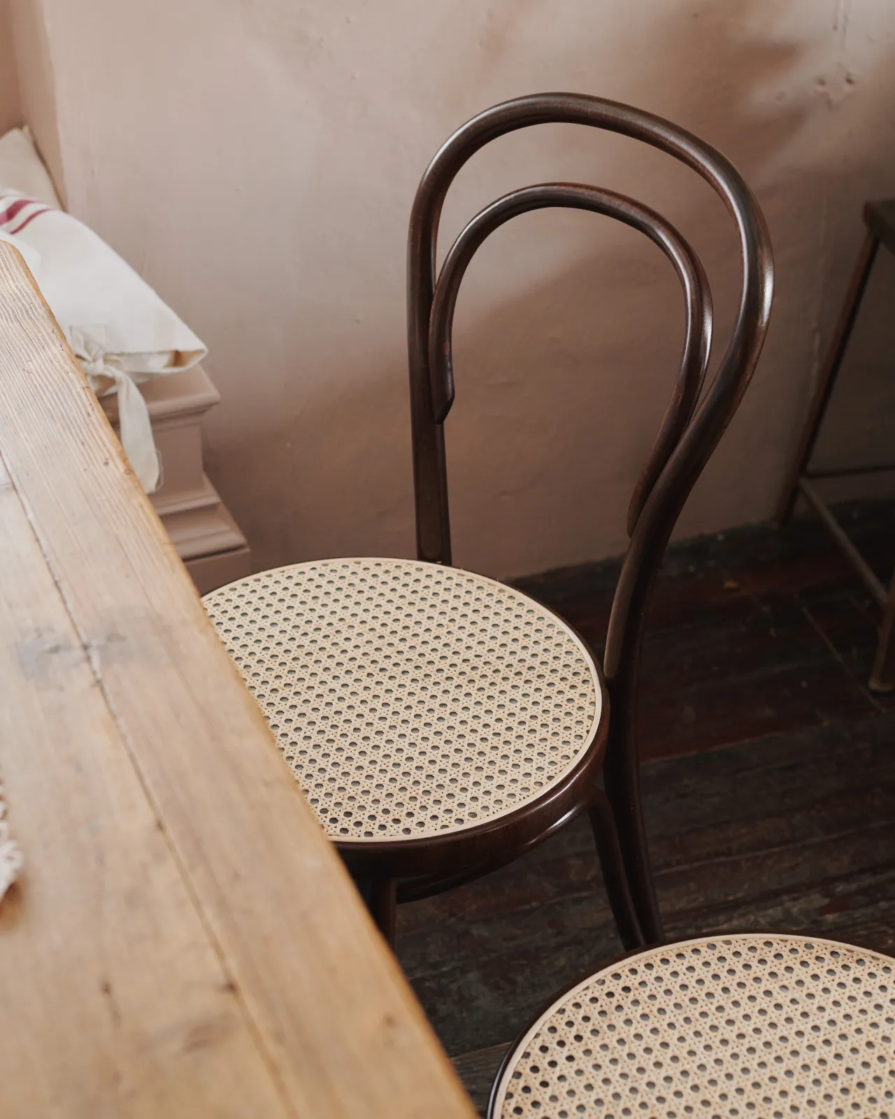 An oblique view of a café-style bentwood chair with a dark stained frame and light woven rattan seat mesh.