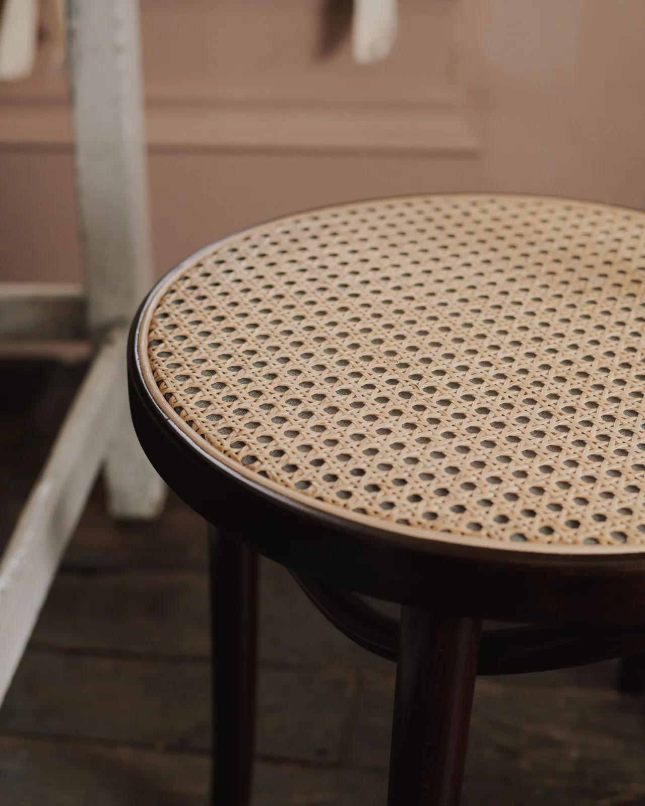A close-up view of a light woven rattan seat mesh on a dark stained frame.