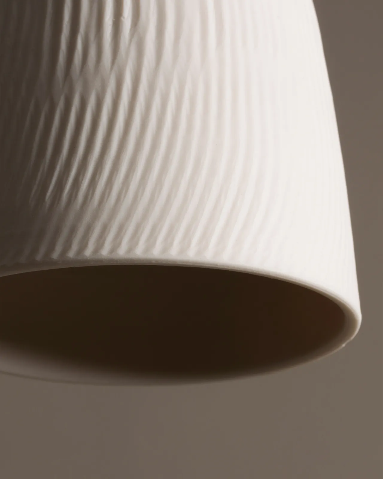 A close-up view of an unglazed chattered beaker porcelain pendant light.