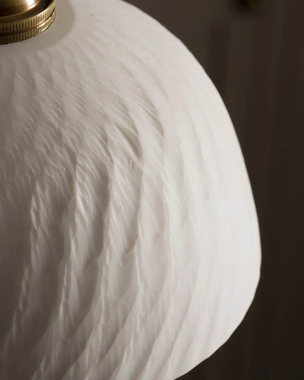 A close-up view of an unglazed chattered rice bowl porcelain pendant light.