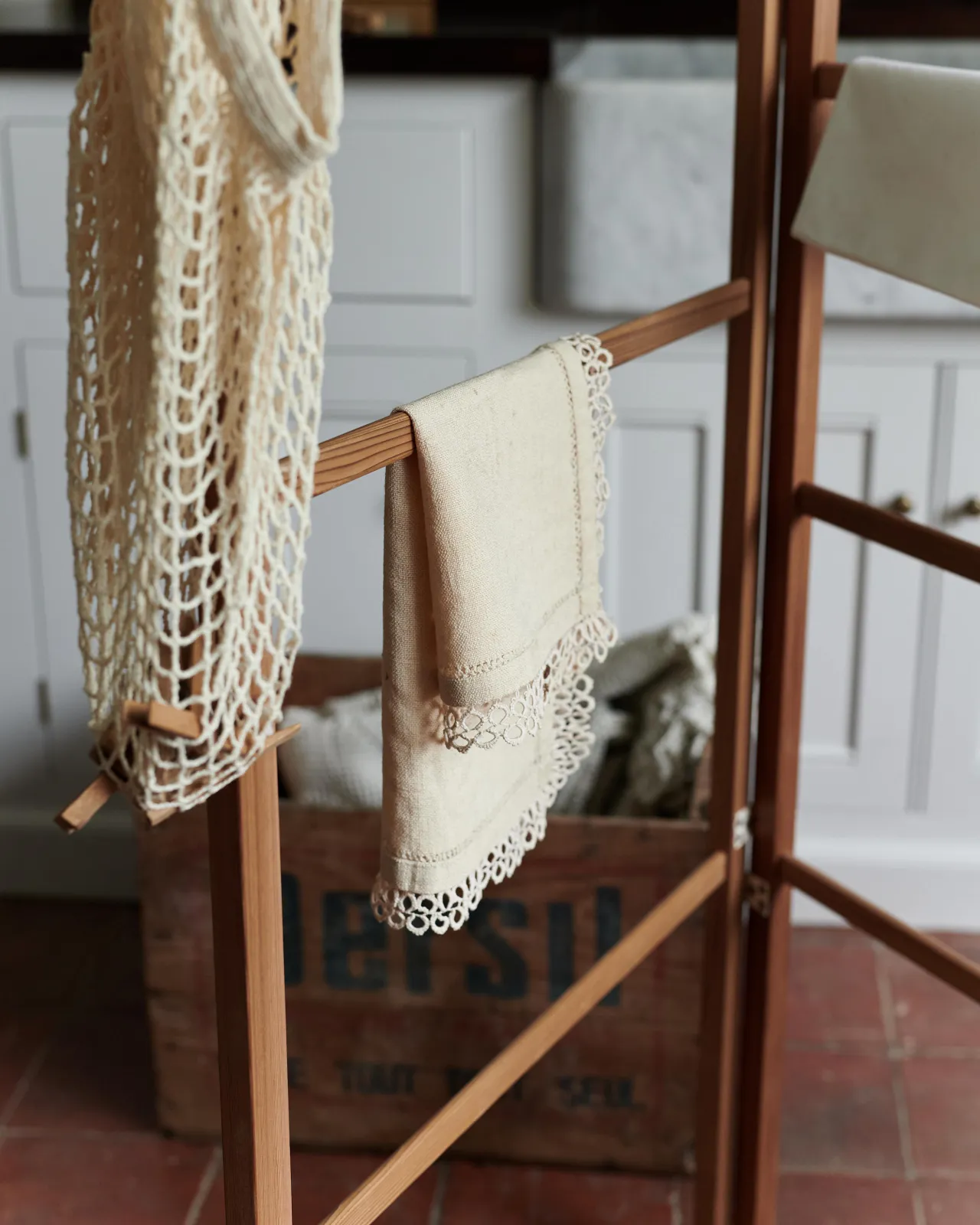 A close-up view of vintage linens draped over a wooden clothes horse.