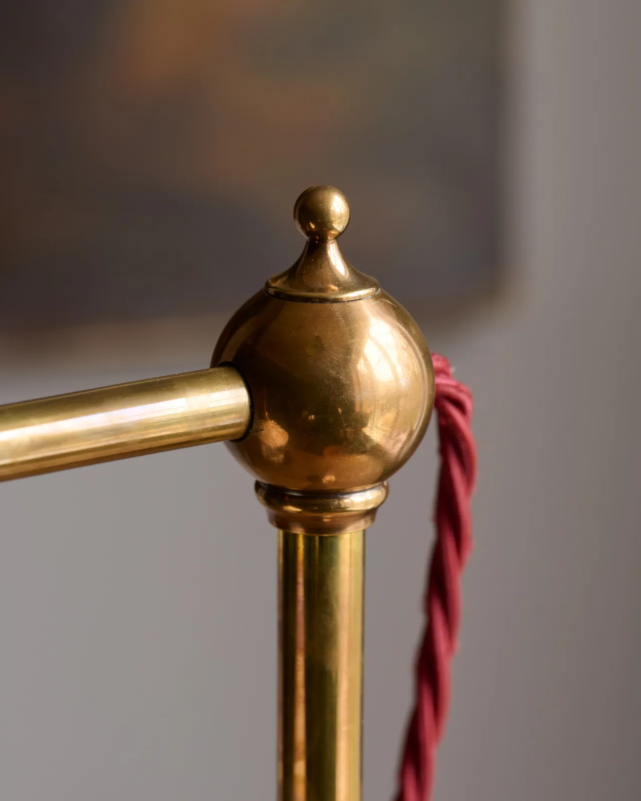A close-up view of a pointed brass finial with red twisted fabric flex cord leading into the back.