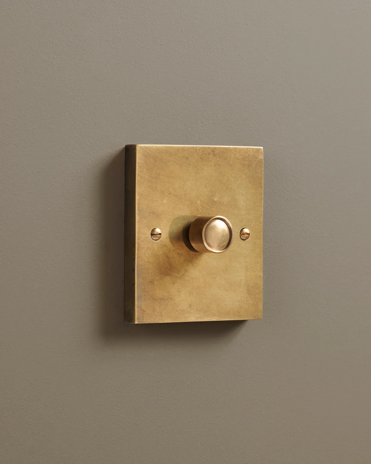 An oblique view of a 1 gang box dimmer switch in a warm burnished brass finish.