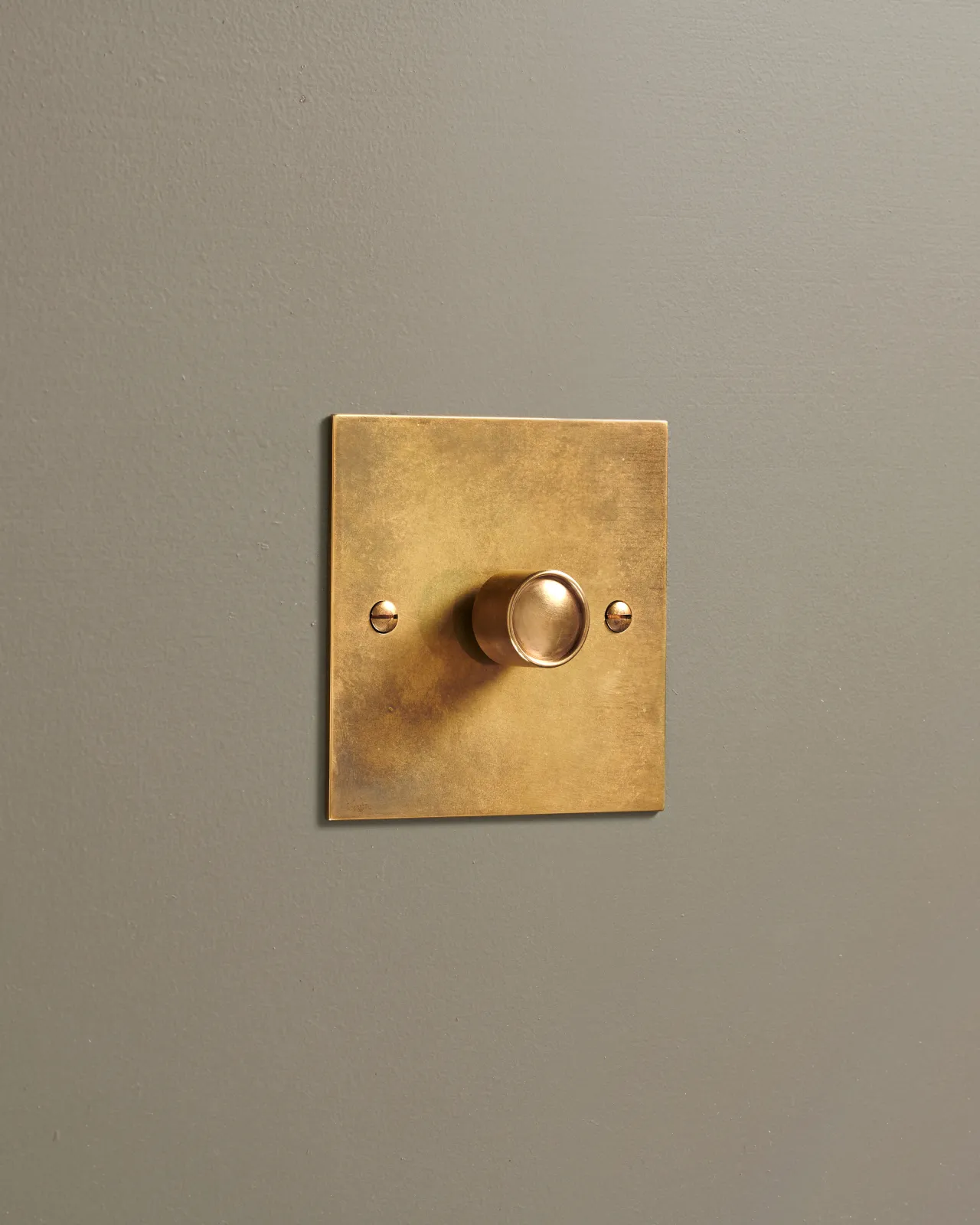 An oblique view of a 1 gang classic dimmer switch in a warm burnished brass finish.