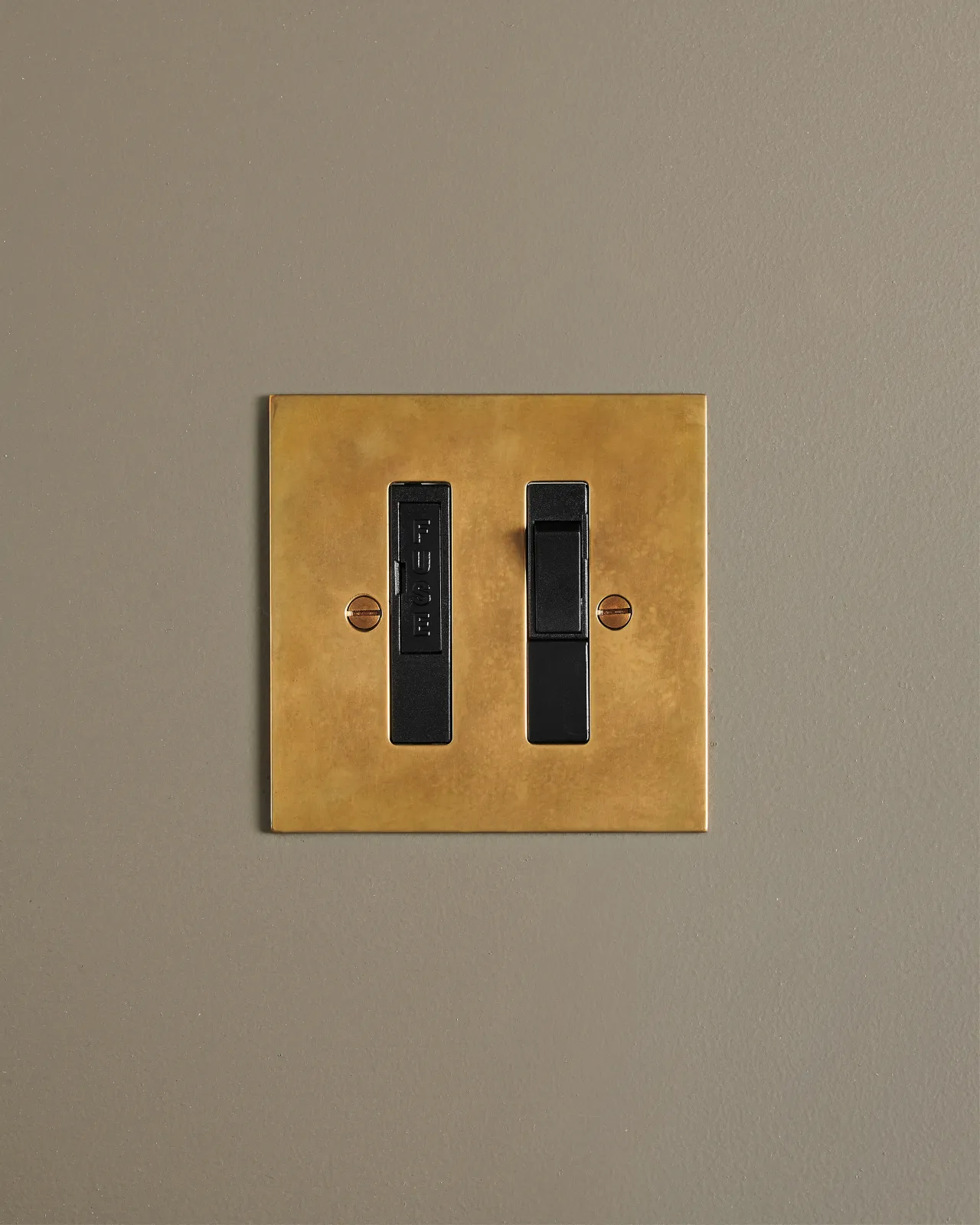 A straight-on view of a classic fused connection switch in a warm burnished brass finish.