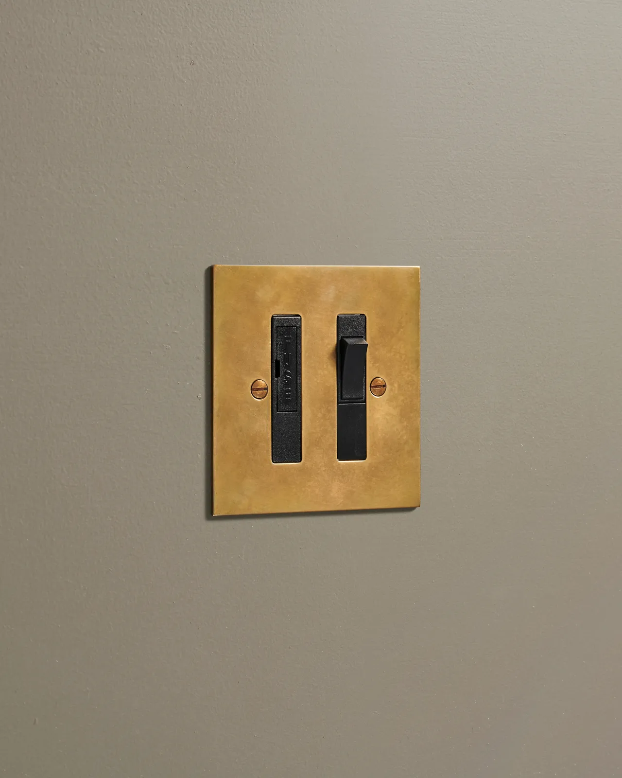 An oblique view of a classic fused connection switch in a warm burnished brass finish.