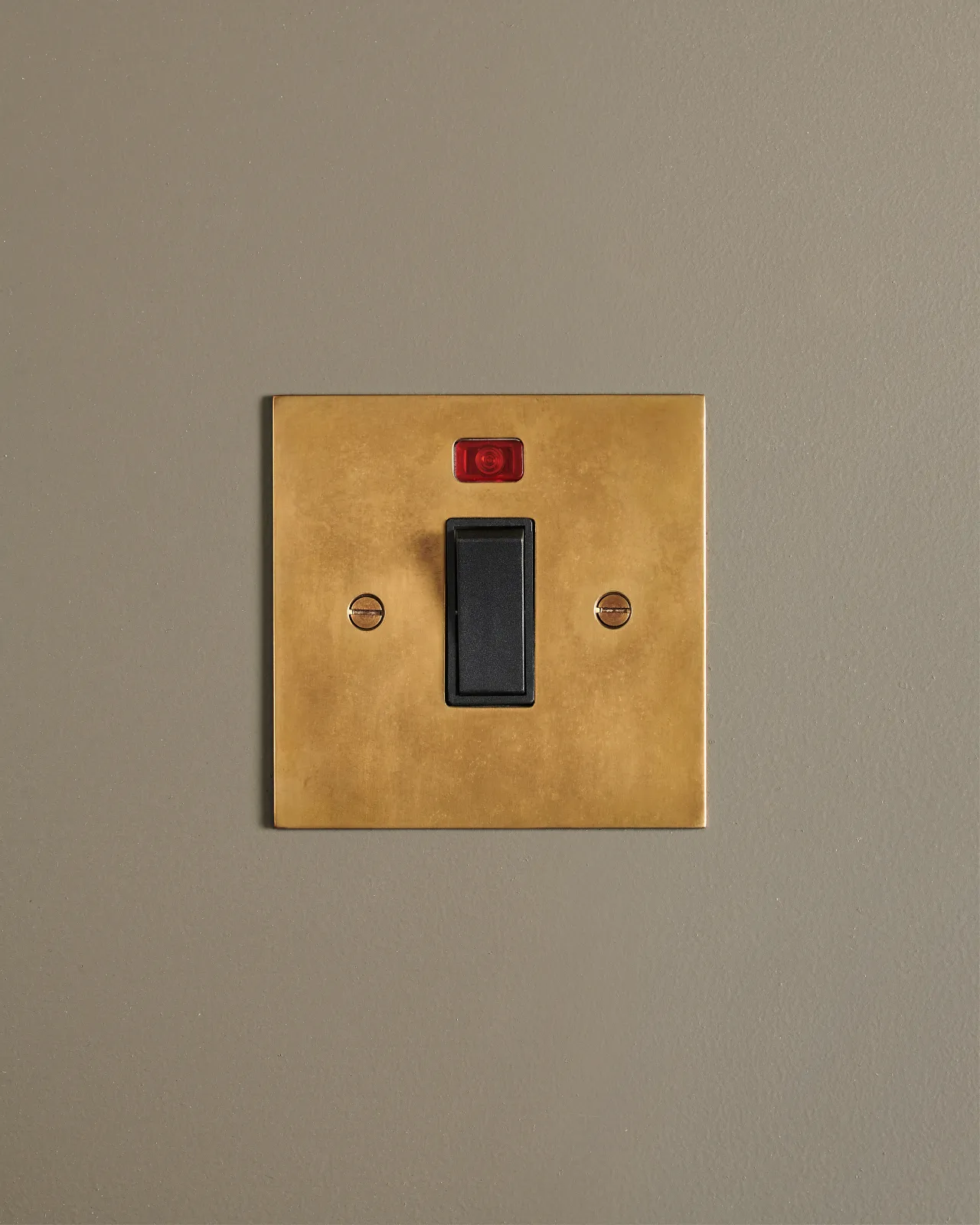 A straight-on view of a classic 32 amp cooker switch in a warm burnished brass finish.