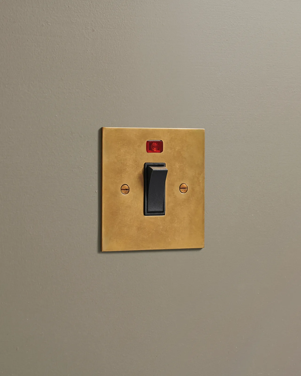 An oblique view of a classic 32 amp cooker switch in a warm burnished brass finish.