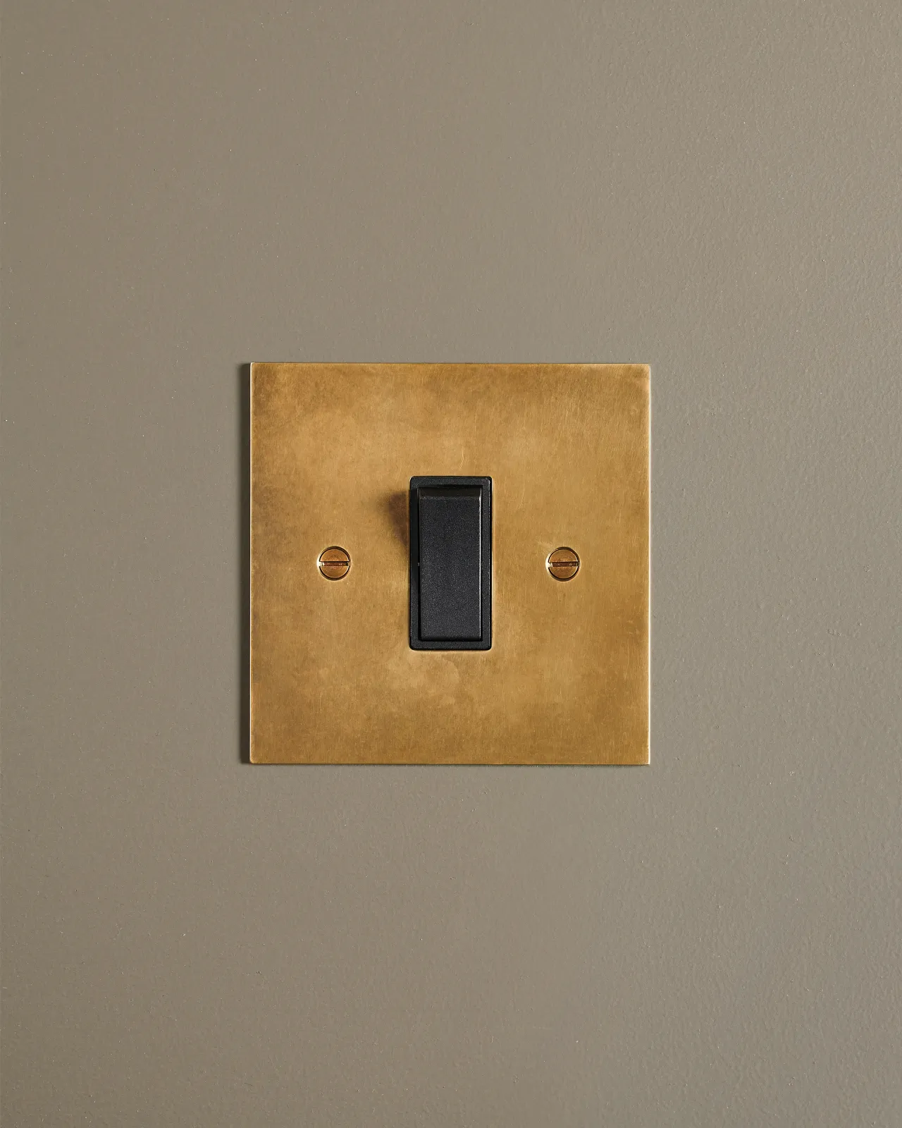 A straight-on view of a classic 20 amp switch in a warm burnished brass finish.