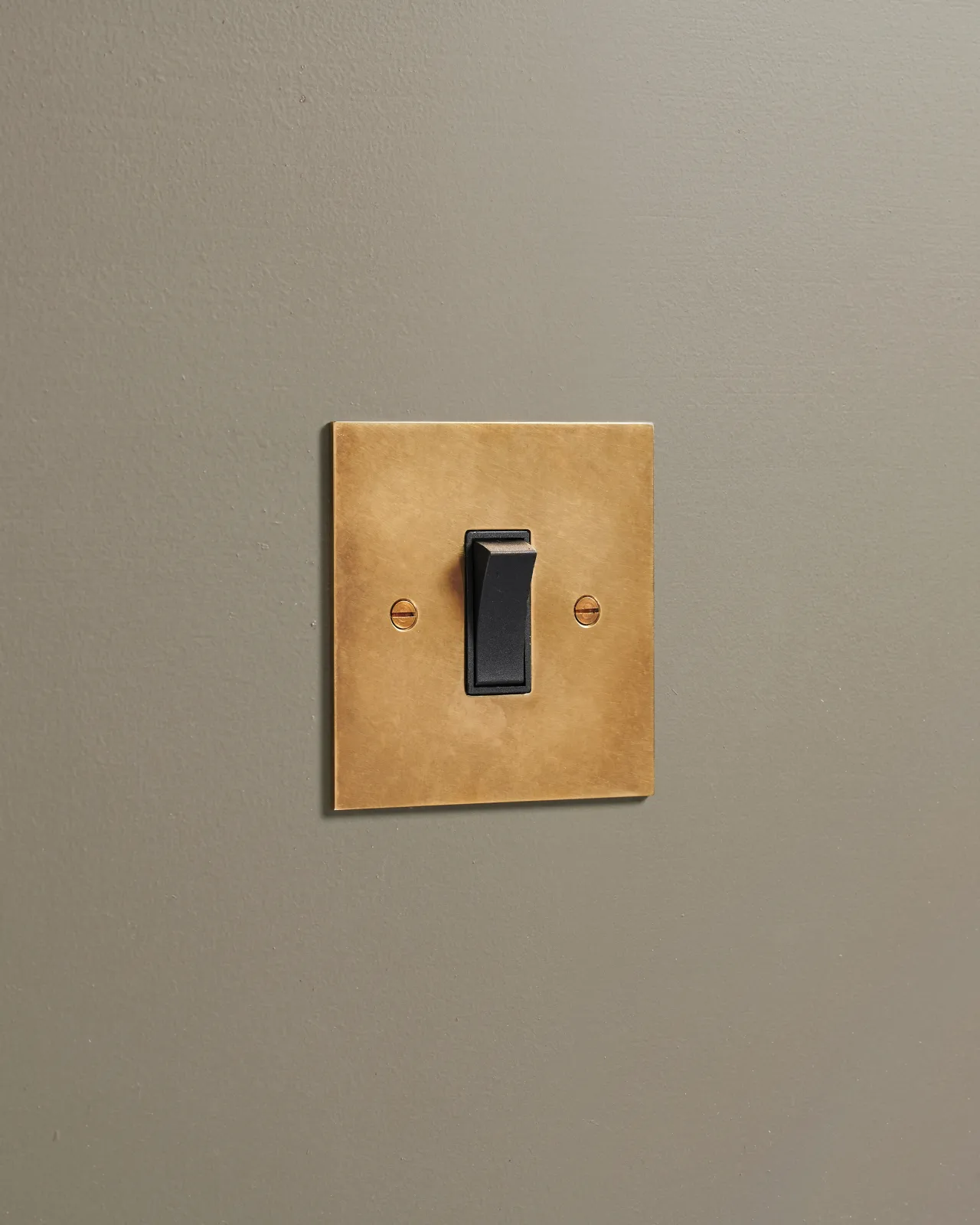An oblique view of a classic 20 amp switch in a warm burnished brass finish.