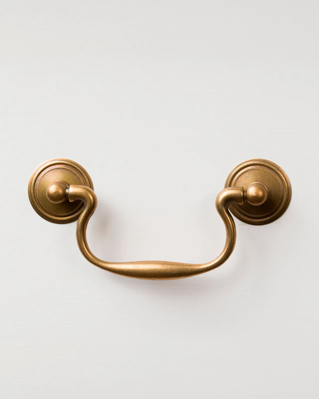A Georgian-style swing handle for a kitchen cupboard or drawer in a burnished 'Bella' brass finish.