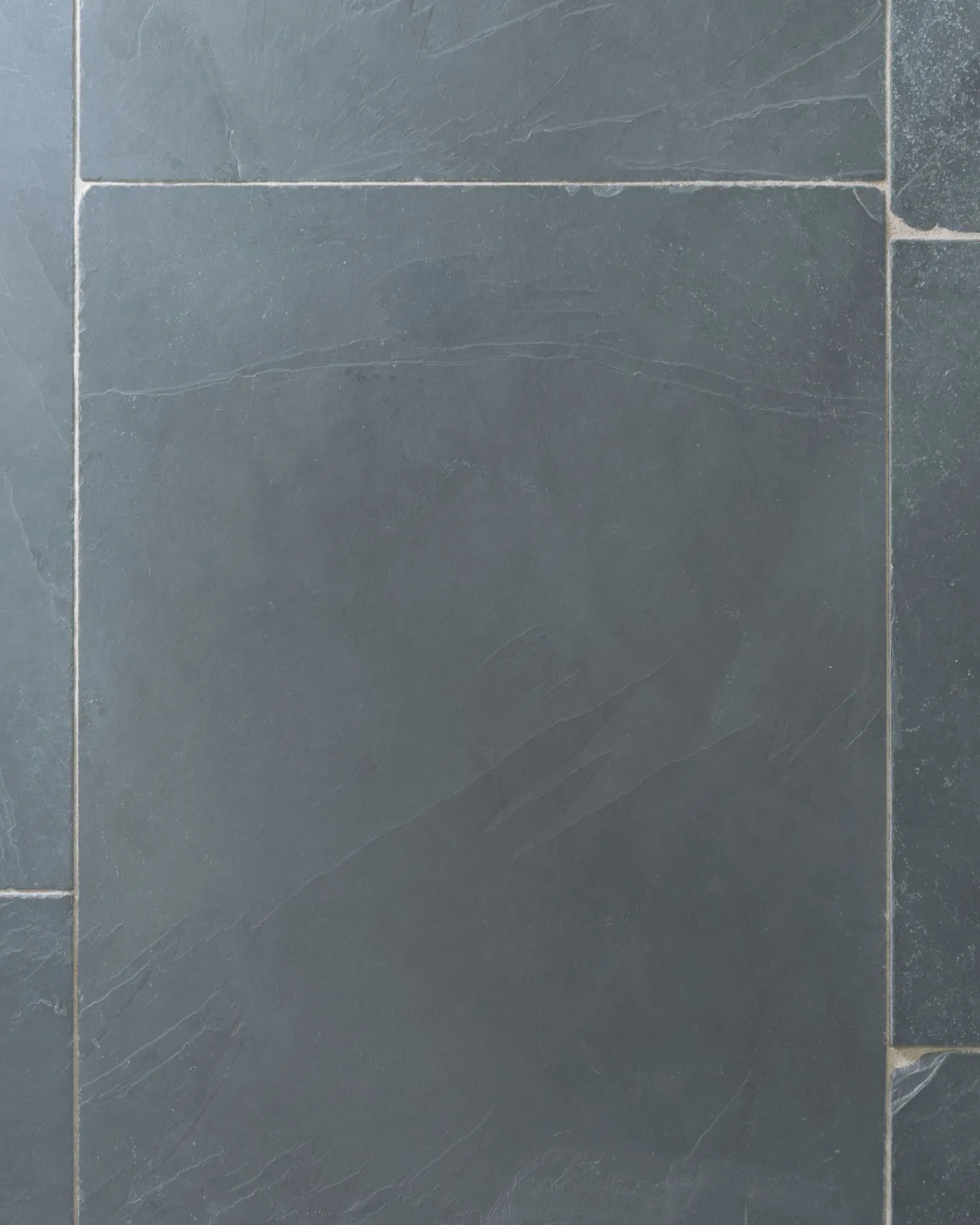 A close-up overhead view of a grey tumbled slate floor.