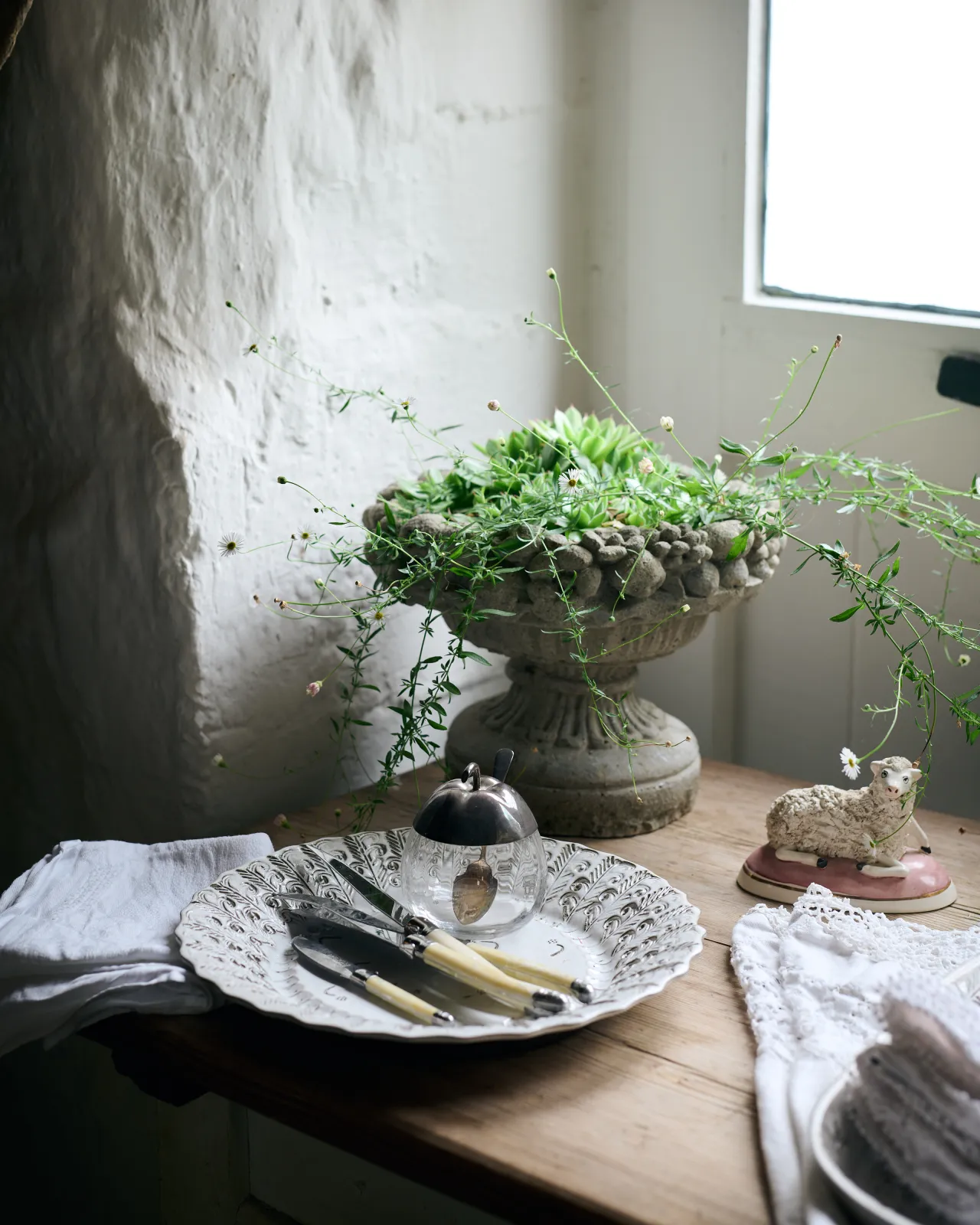An oblique view of a round handmade bohemian-style white ceramic platter on a vintage farmhouse table.