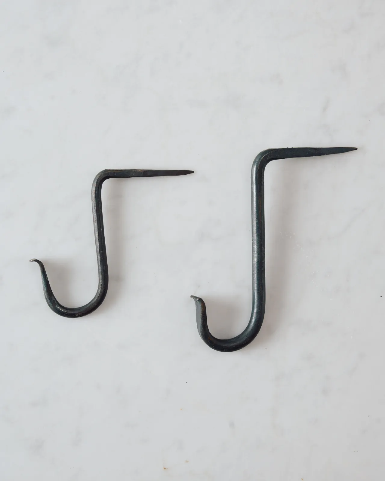 Two iron beam hooks with curled ends, one small and one large.