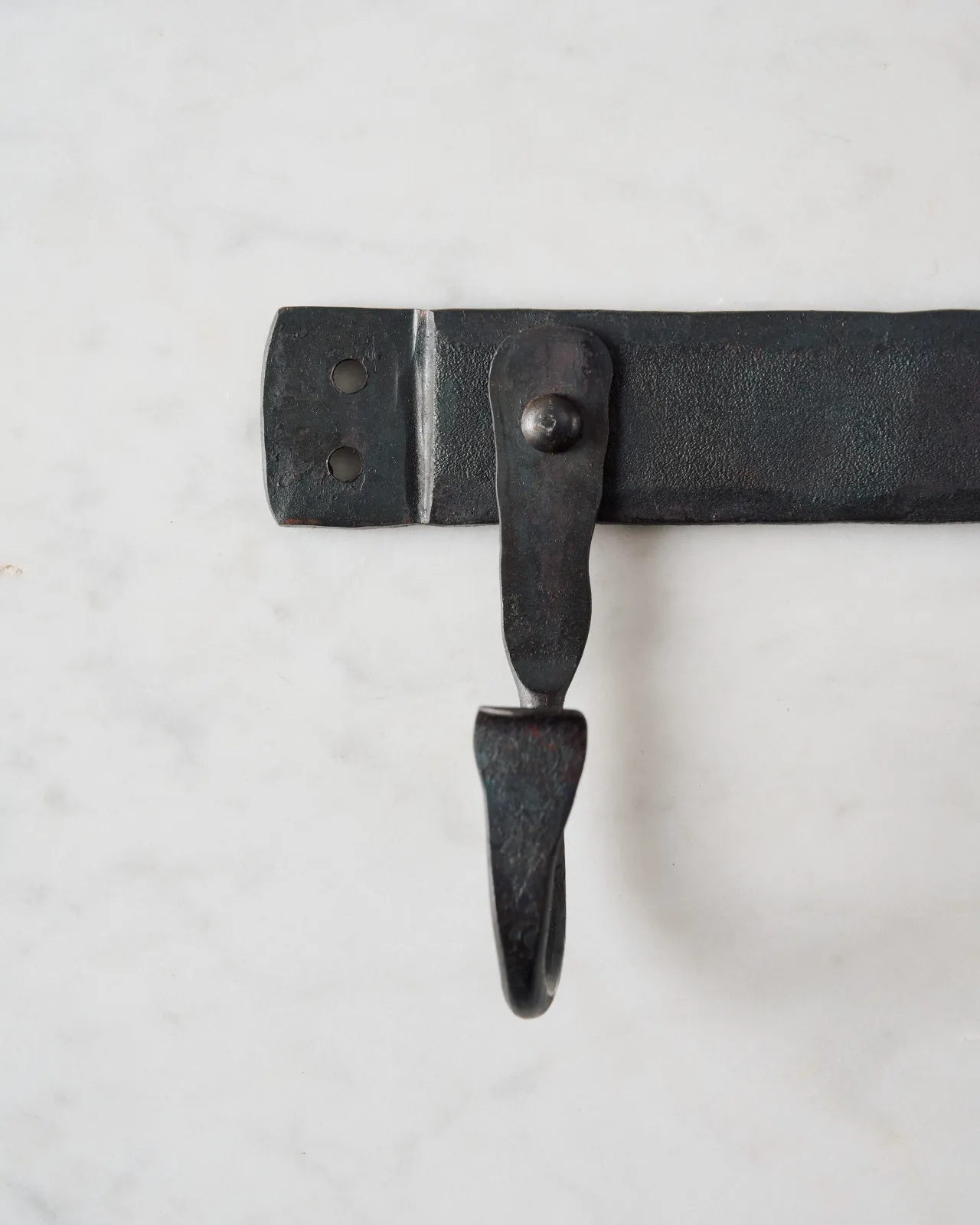 A close-up front profile view of an end hook on a wrought iron hook rack.