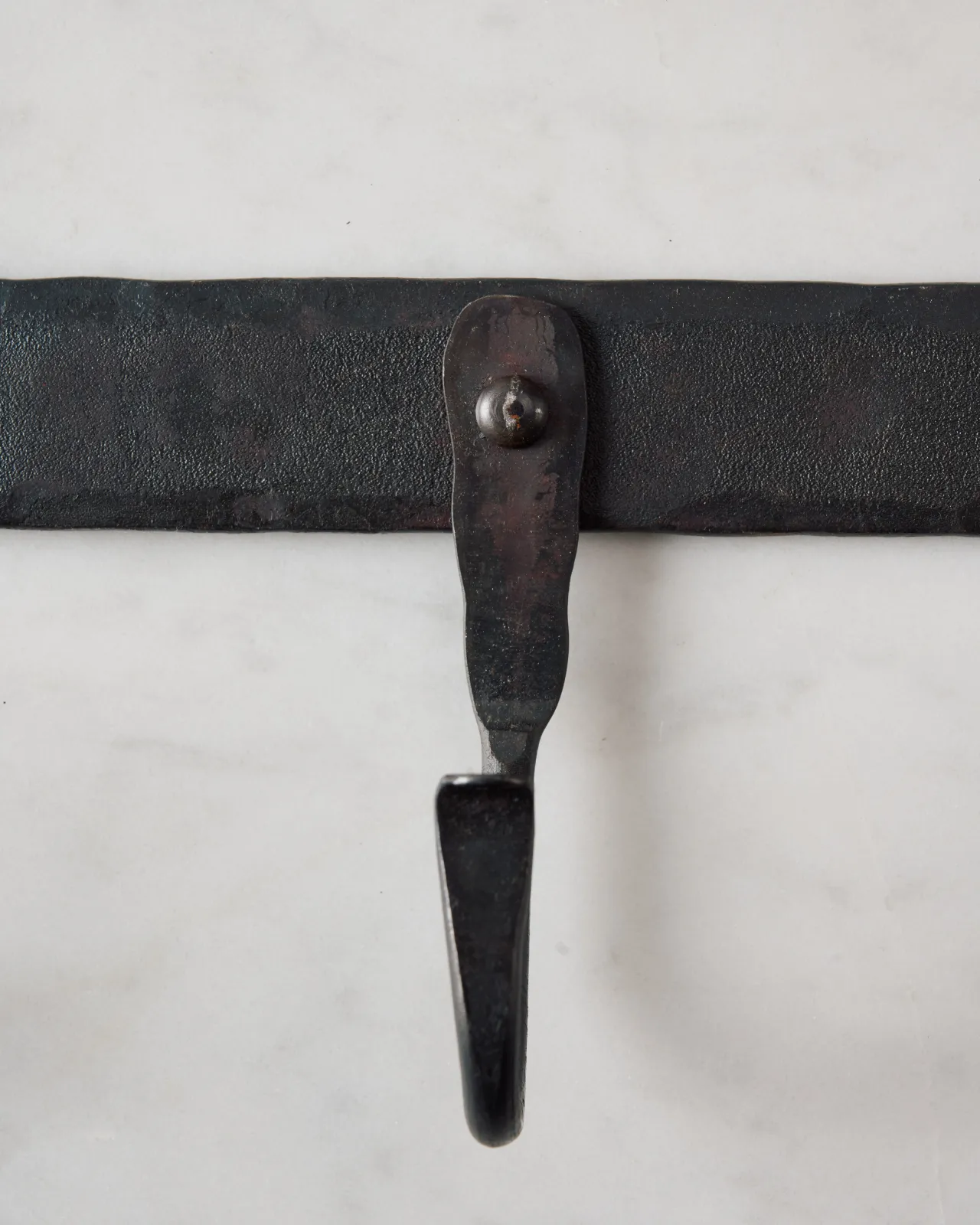 A close-up front profile view of a hook on a wrought iron hook rack.