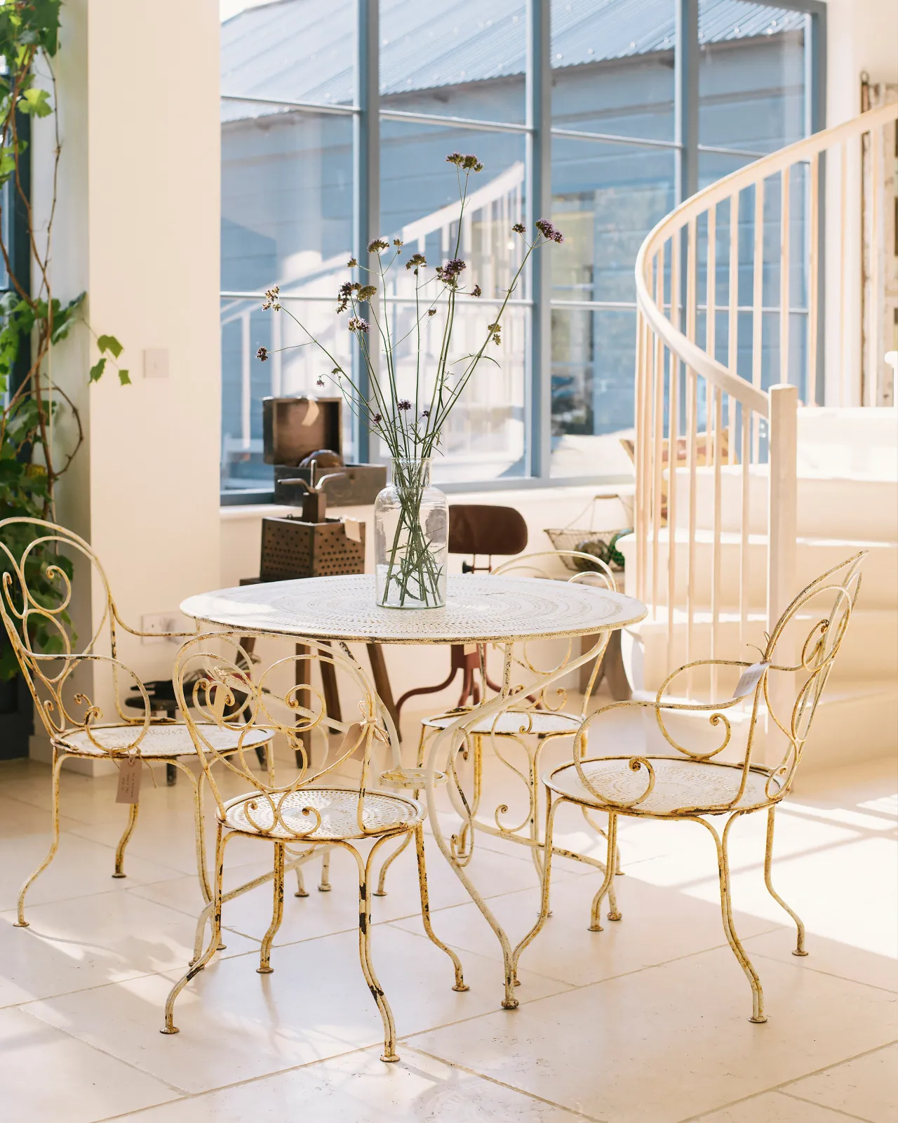 A fresh and airy room with smooth, cream Light Jerusalem Limestone flooring and a rustic, antique metal dining table and set of four chairs.