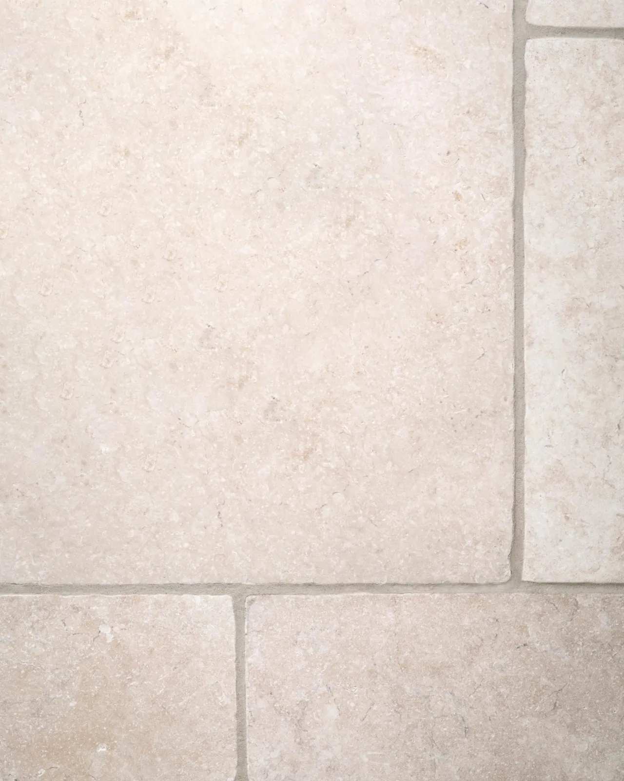 A close-up overhead view of Light Jerusalem Limestone flooring, showing the mottled cream colour and smooth texture.