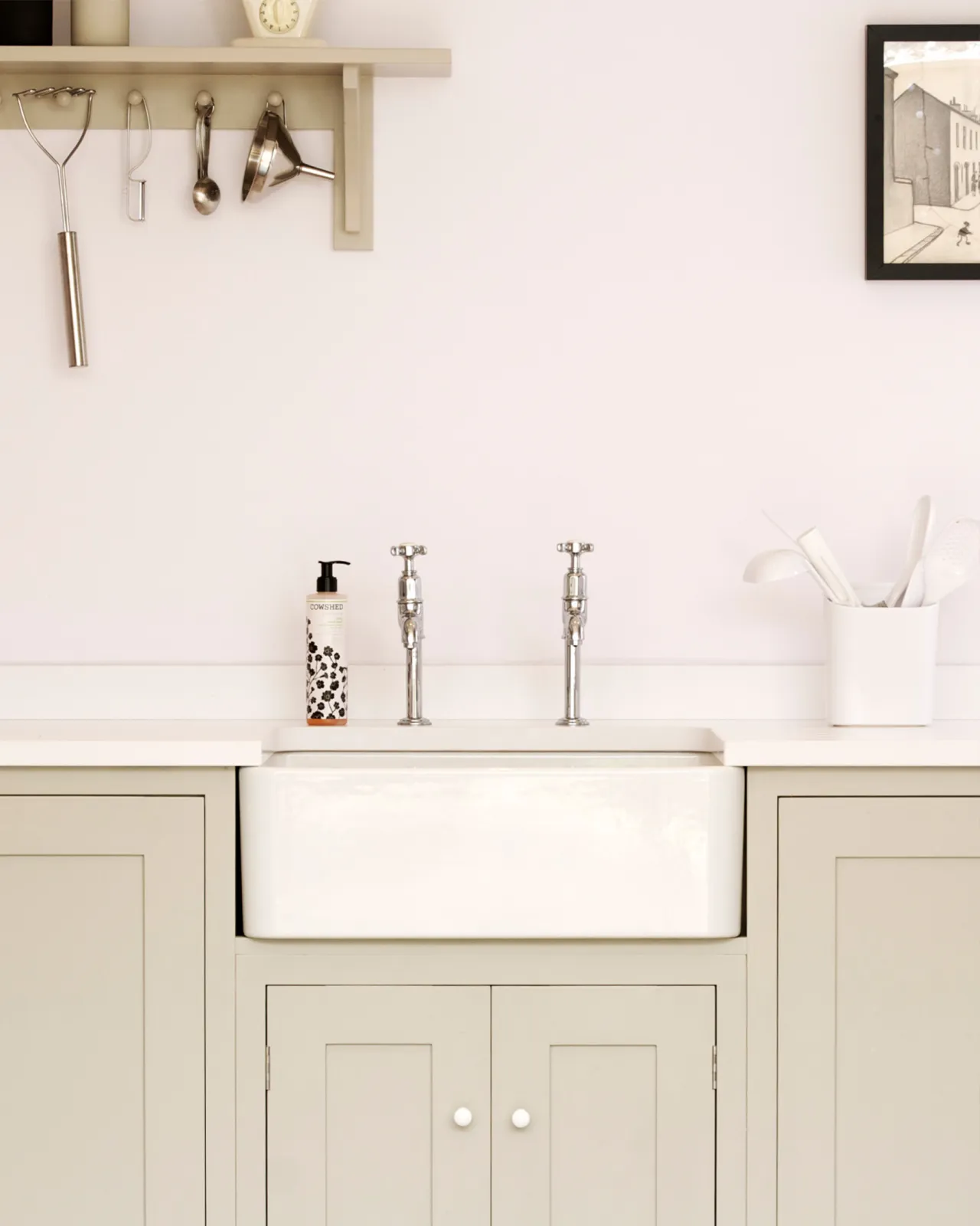 A straight-on view of a pair of traditional-style chrome bibcock taps with crosshead handles in a simple Shaker kitchen.