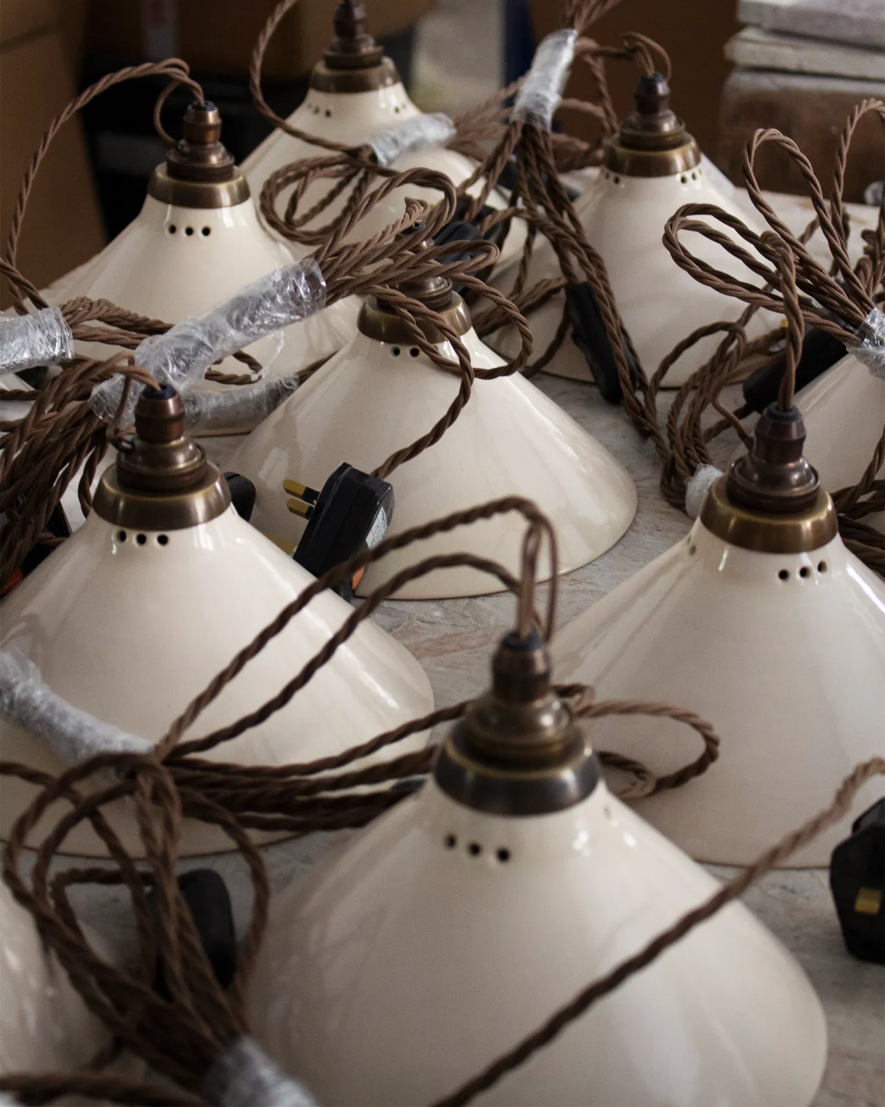 A collection of small plug-in lights with a cream glazed shades, brown twisted fabric flex cord and brass fittings.