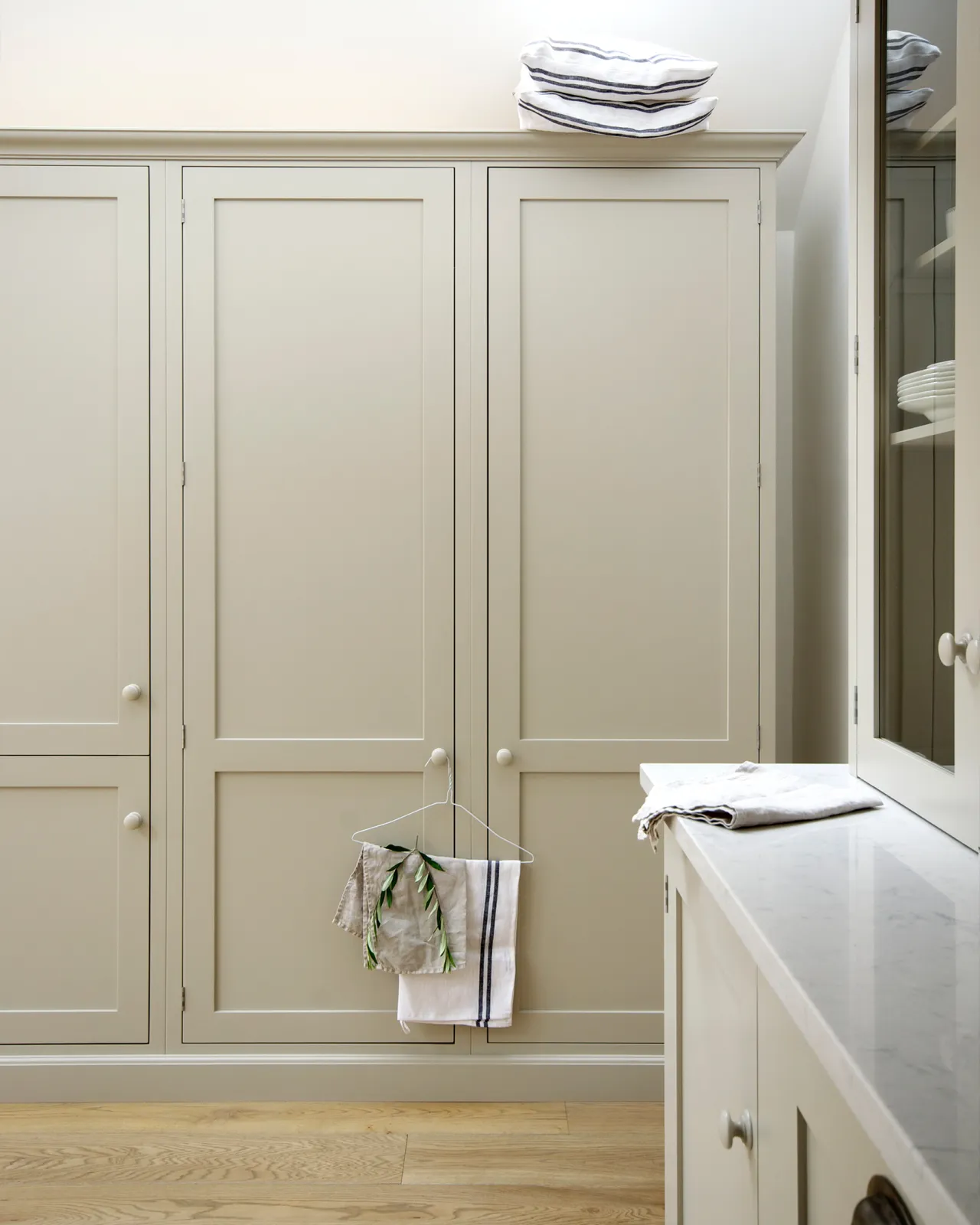 A straight-on view of simple Shaker-style tall pantry cupboards painted in a creamy mushroom colour.