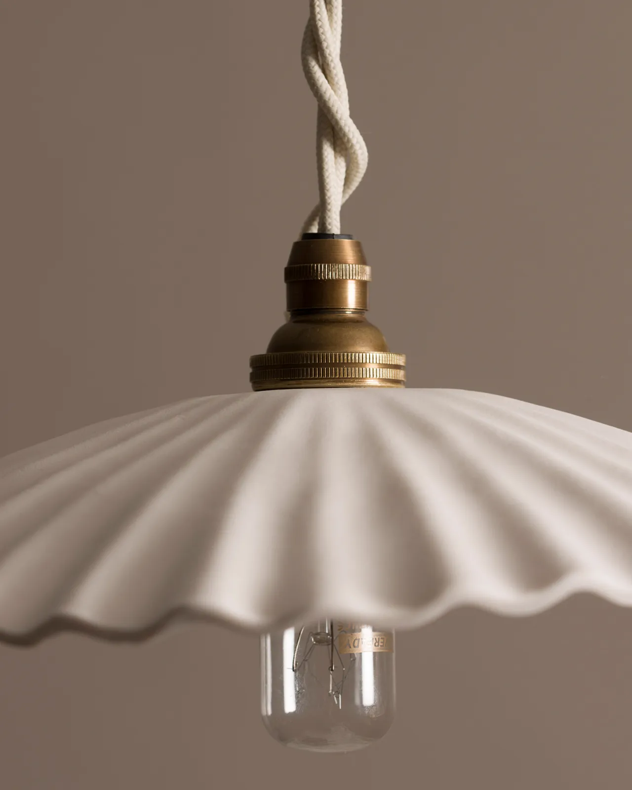 A close-up view of an unglazed porcelain pendant light with narrow pleats.