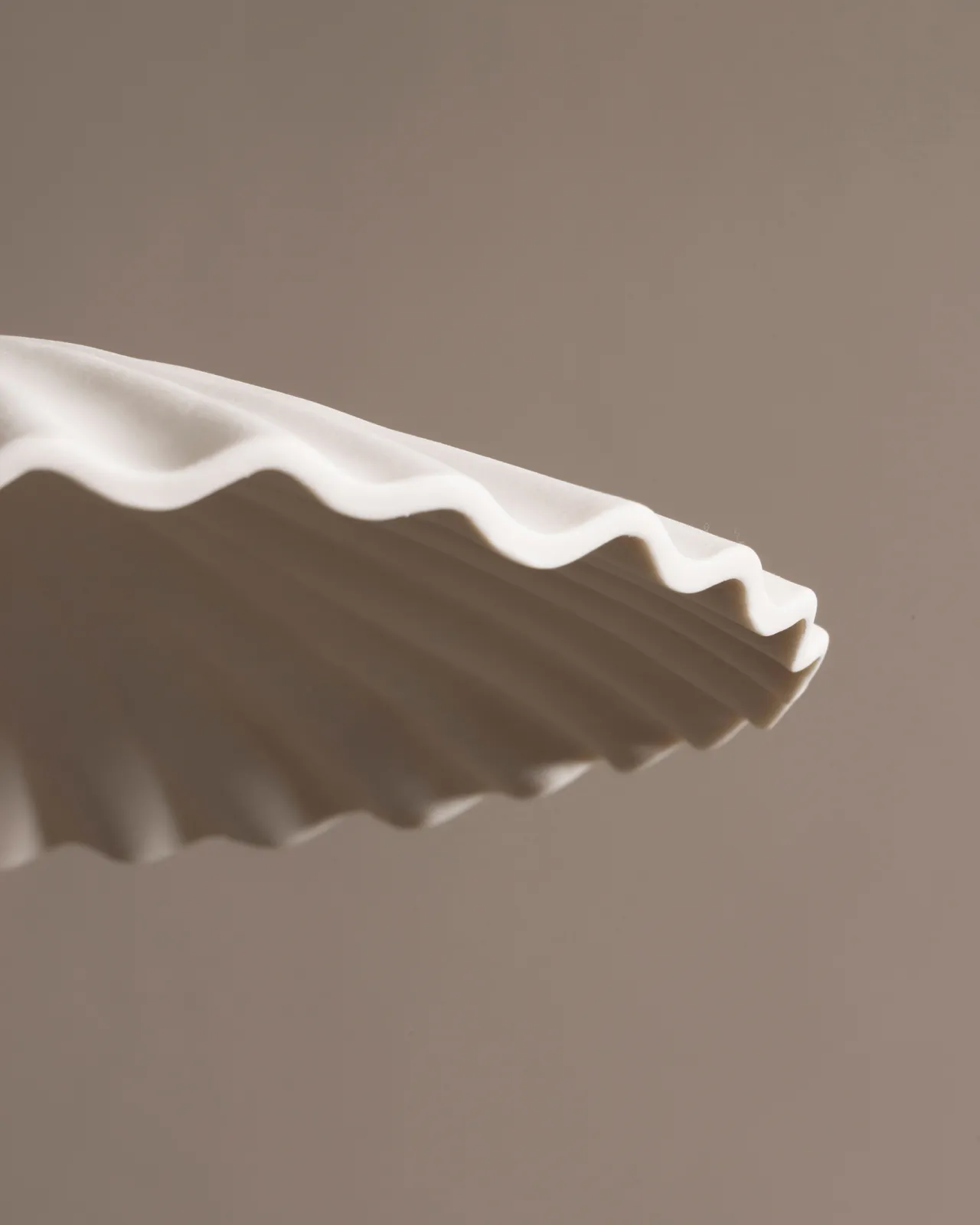 A close-up view of an unglazed porcelain pendant light with narrow pleats.
