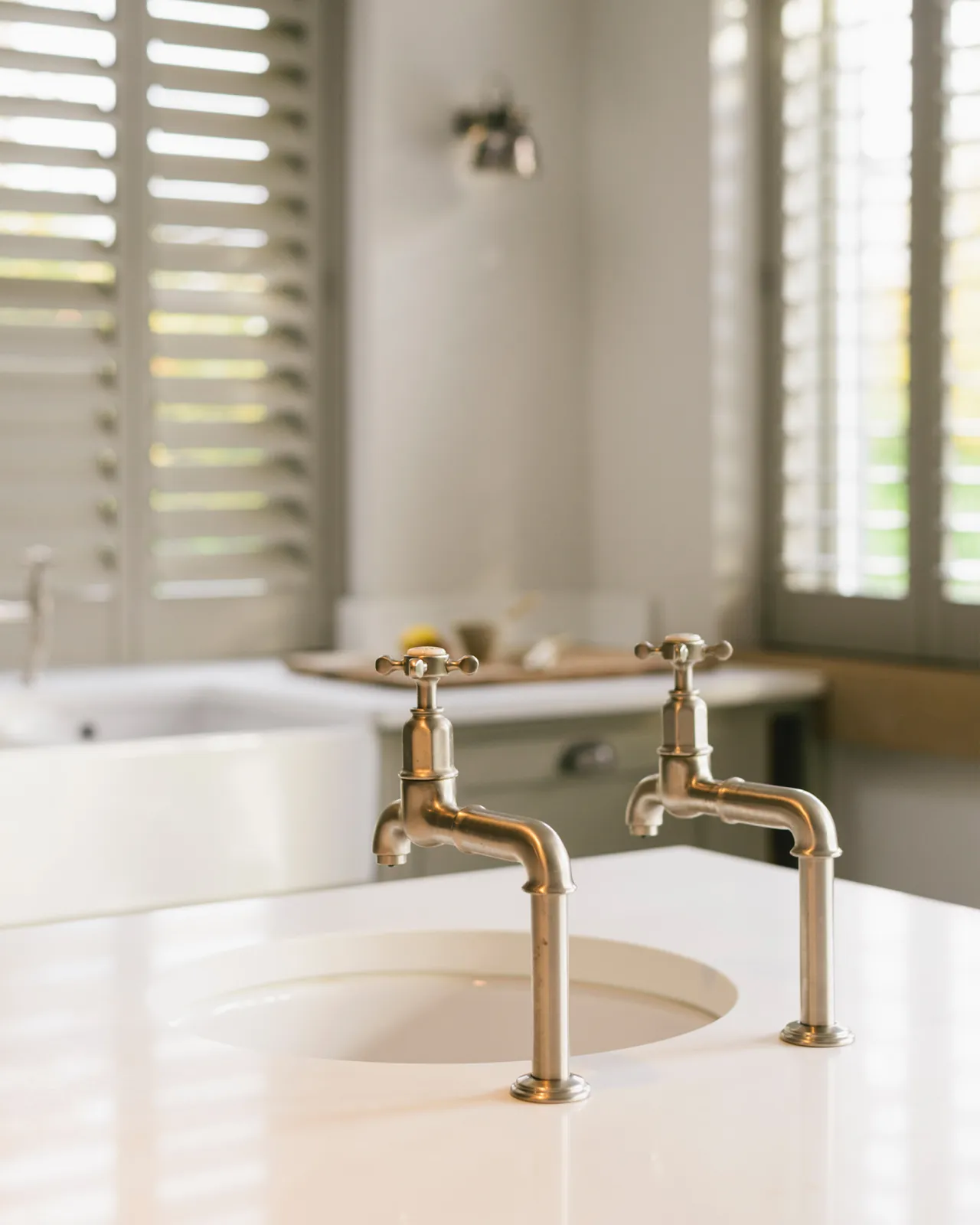 A pair of traditional-style nickel bibcock taps with crosshead handles, viewed from behind.