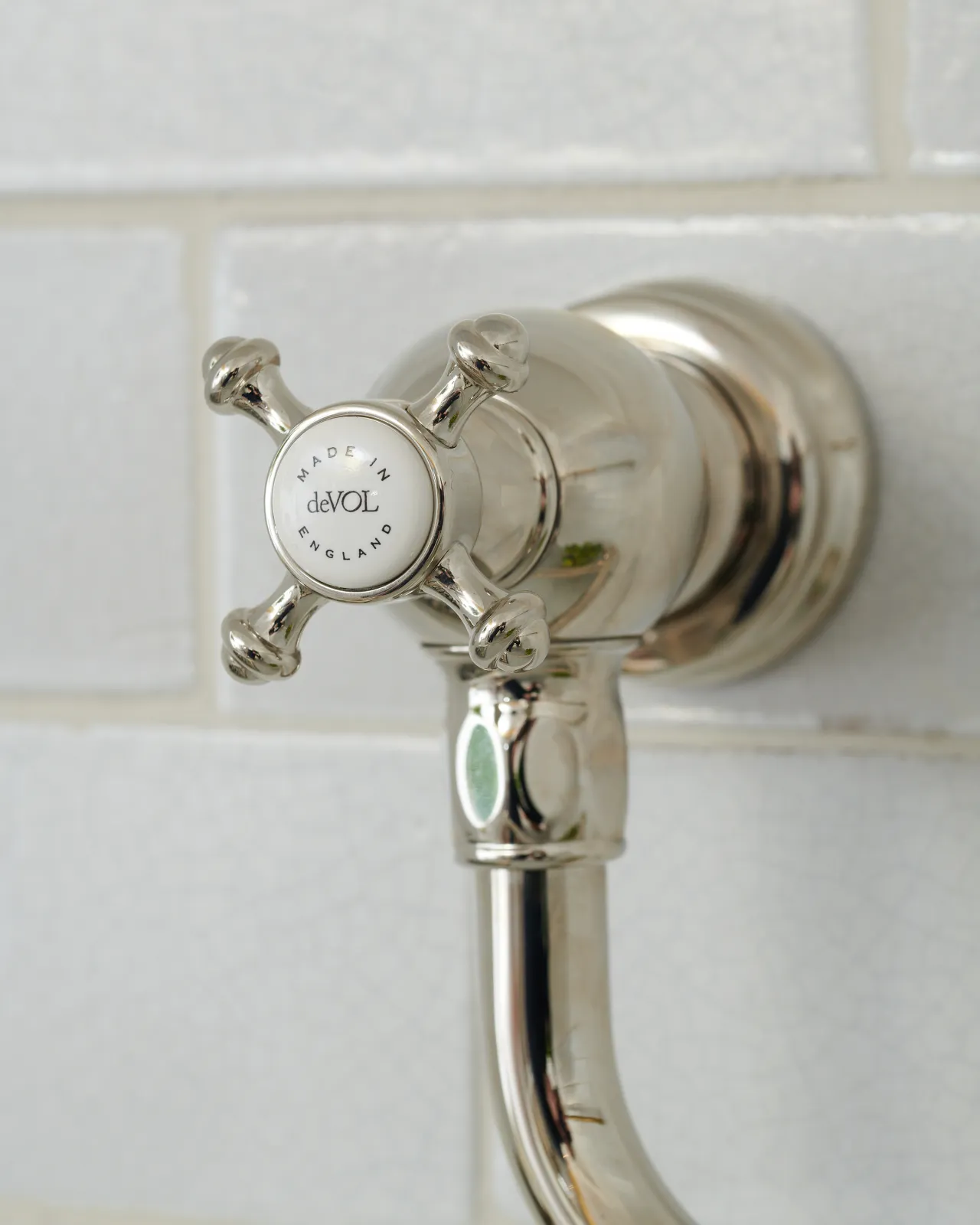 A close-up view of the crosshead handle at the base of a traditional-style nickel pot filler tap, a 'deVOL' logo can be seen in the centre of the handle.