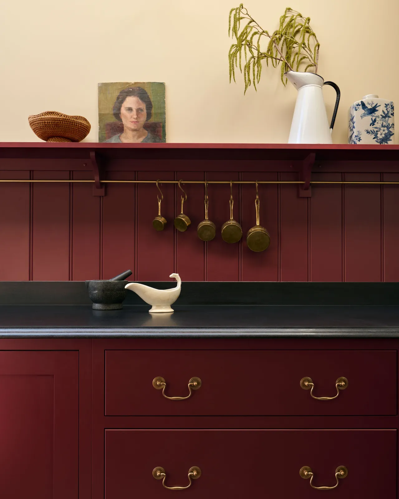 A close-up view of red painted Shaker-style kitchen drawers with a black granite worktop and red tongue and groove panelling above.
