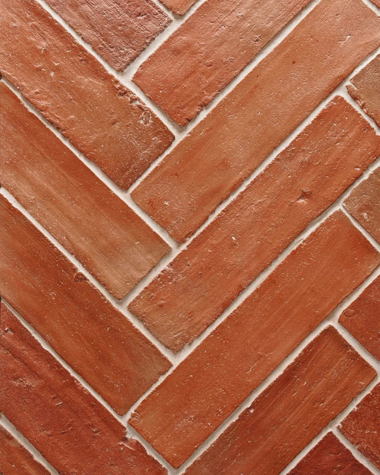A close-up overhead view of parquet terracotta flooring with a rich waxed finish.
