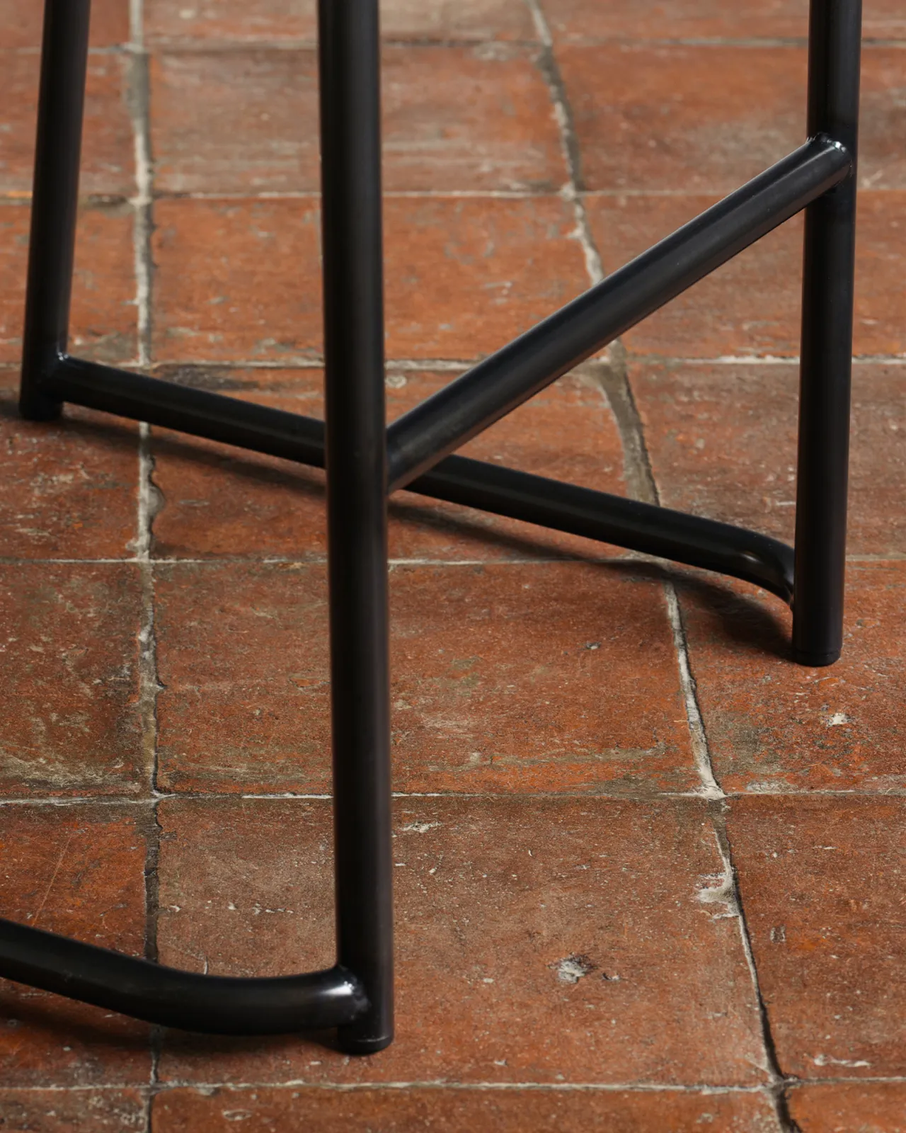 A close-up view of a black tubular metal frame from an industrial bar stool.