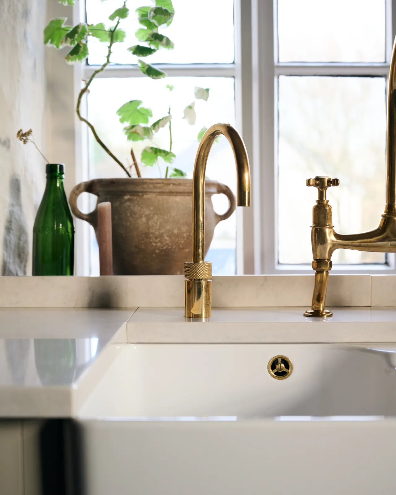 A contemporary-style brass tap with a ring of red light emanating from under a knurled cuff. Boiling water is flowing from the spout.