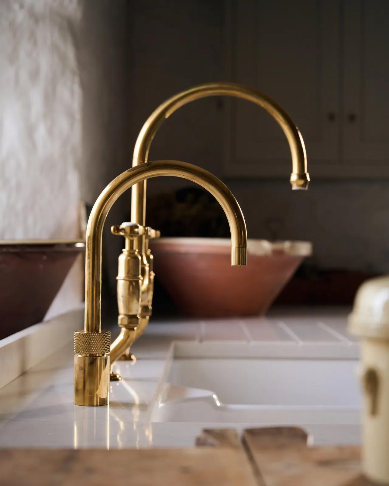 A profile view of a contemporary-style brass tap with a minimal design next to a more traditional brass mixer tap.