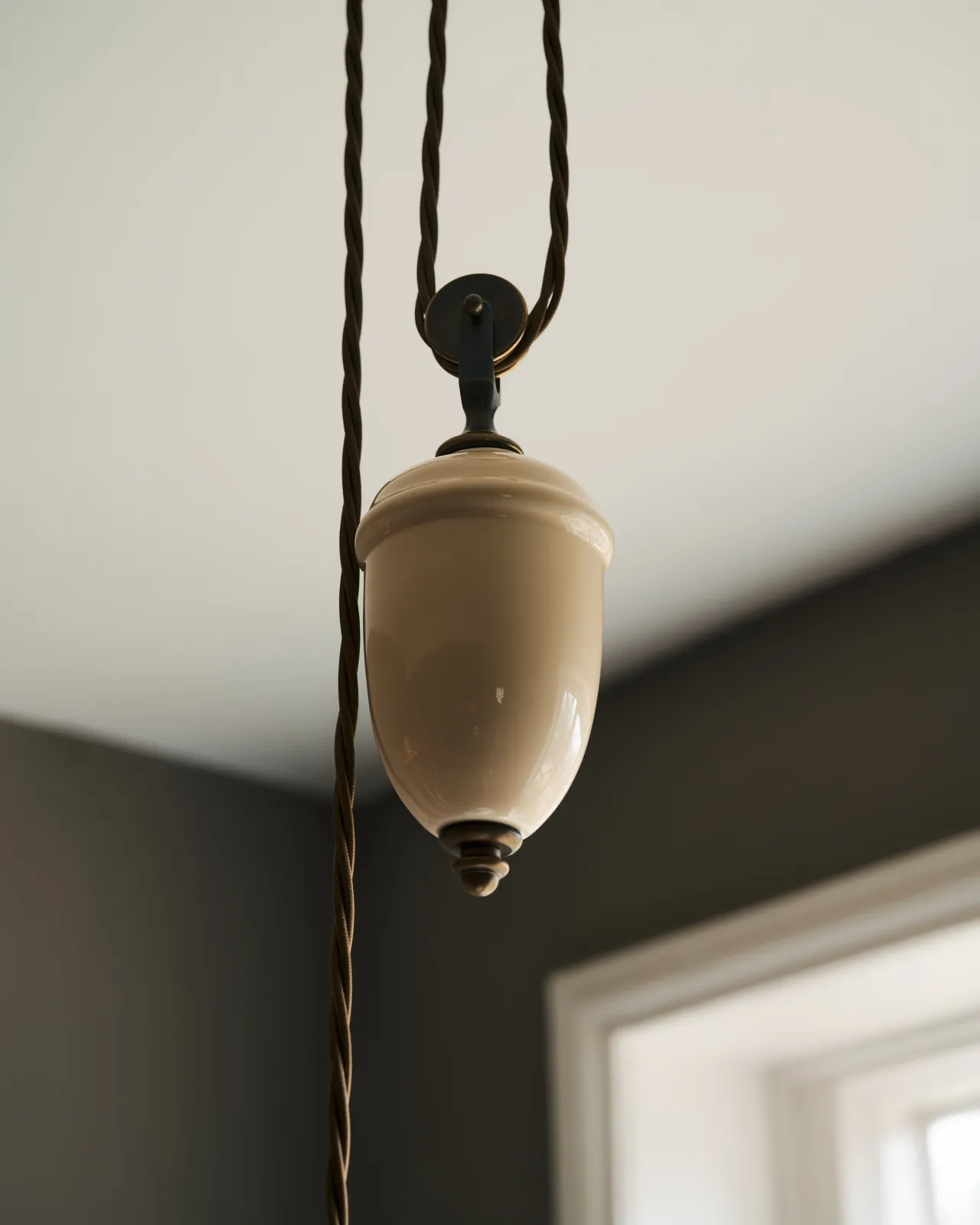 A close-up view of a cream glazed ceramic counterweight for a rise and fall light.
