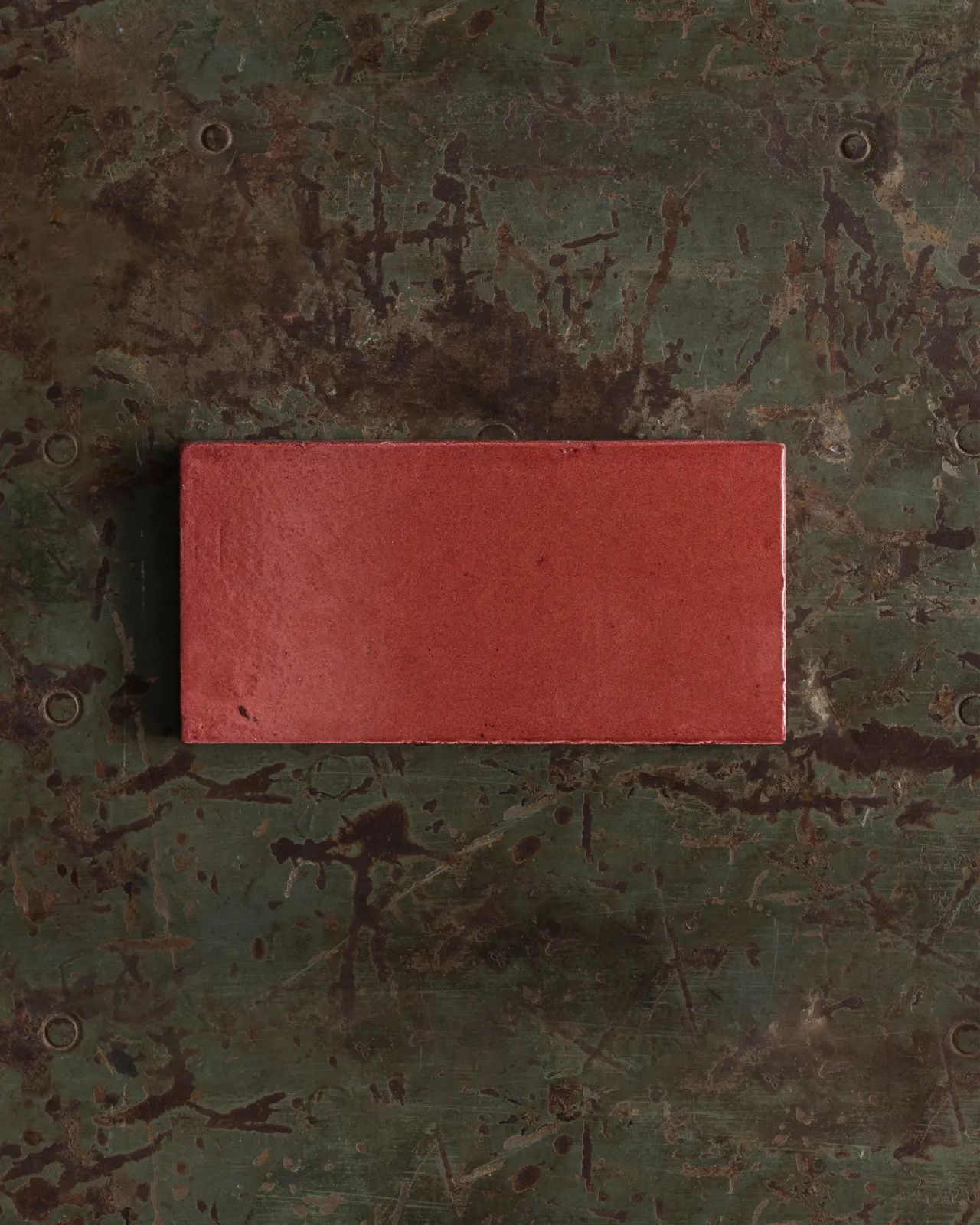 A glossy sepia metro tile on a rustic metallic surface.