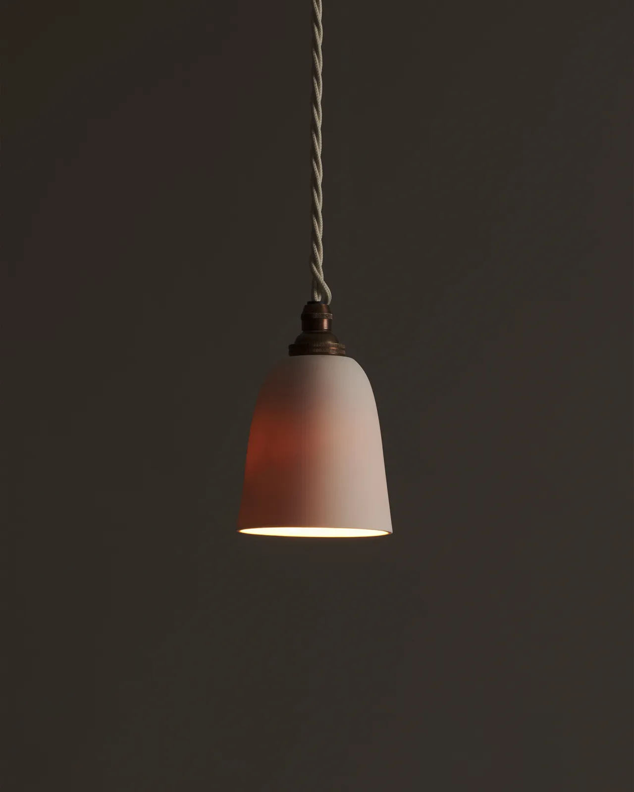 A small plain beaker porcelain pendant with the light on, showing the warm red glow of the translucent surface.