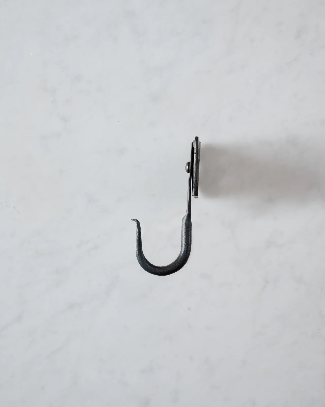 A side profile view of a large iron wall hook with a square-shaped backplate.
