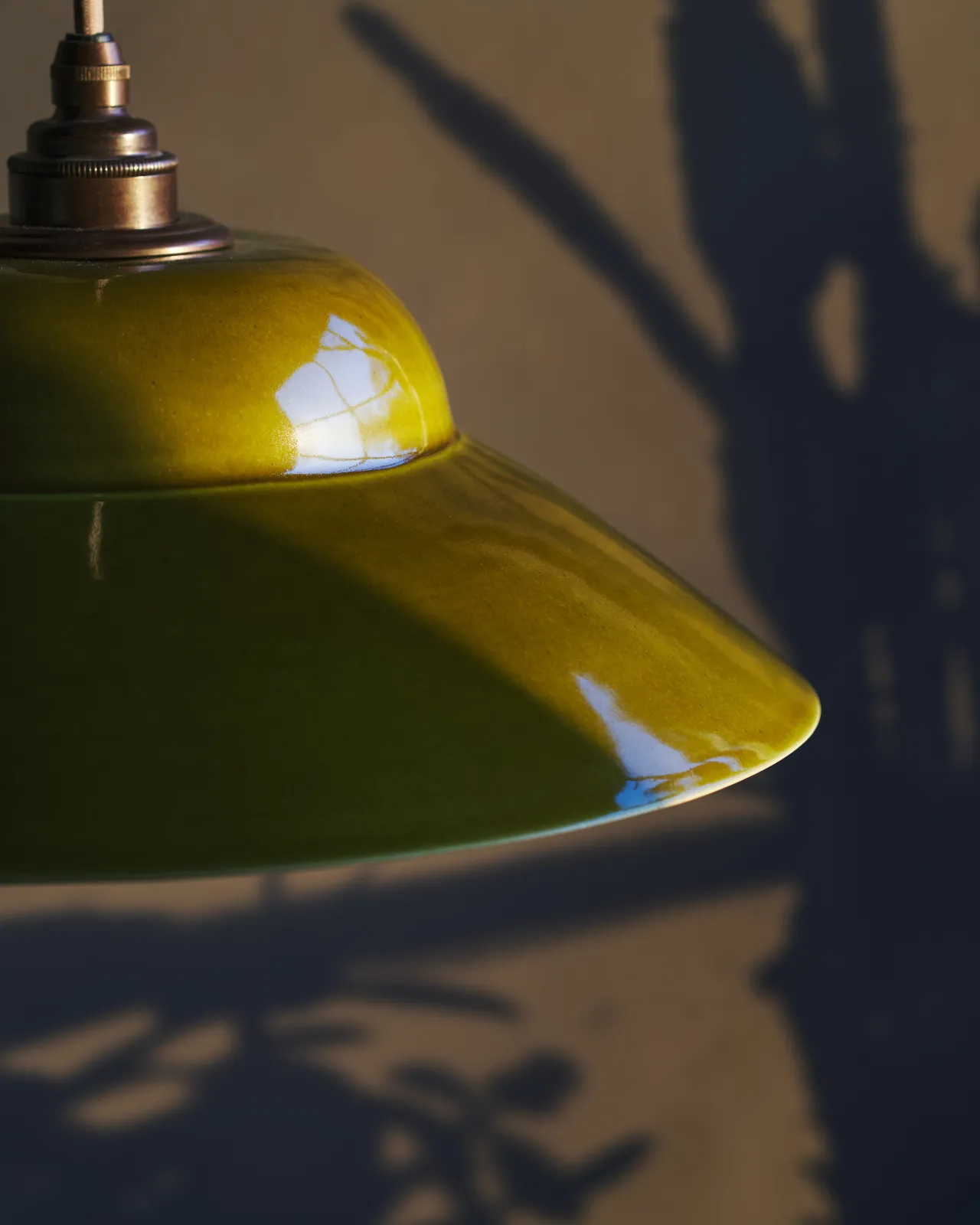 A close-up view of a mid-century-style chartreuse glazed ceramic light shade.