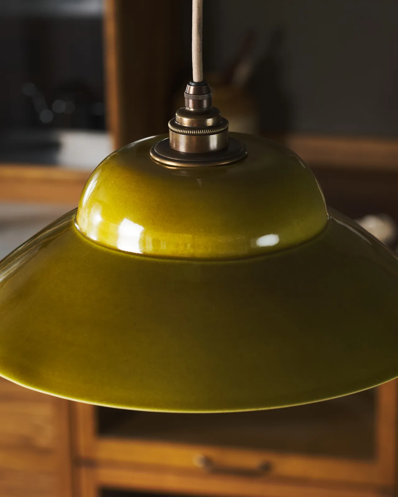 A close-up view of a mid-century-style chartreuse glazed ceramic light shade.